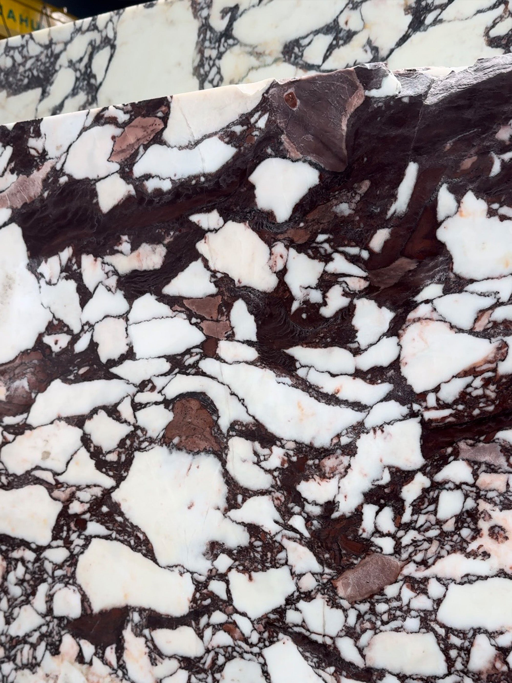 A massive raw Calacatta Viola block at an Italian quarry, showcasing the natural geological layers before custom fabrication by GustavDesign.