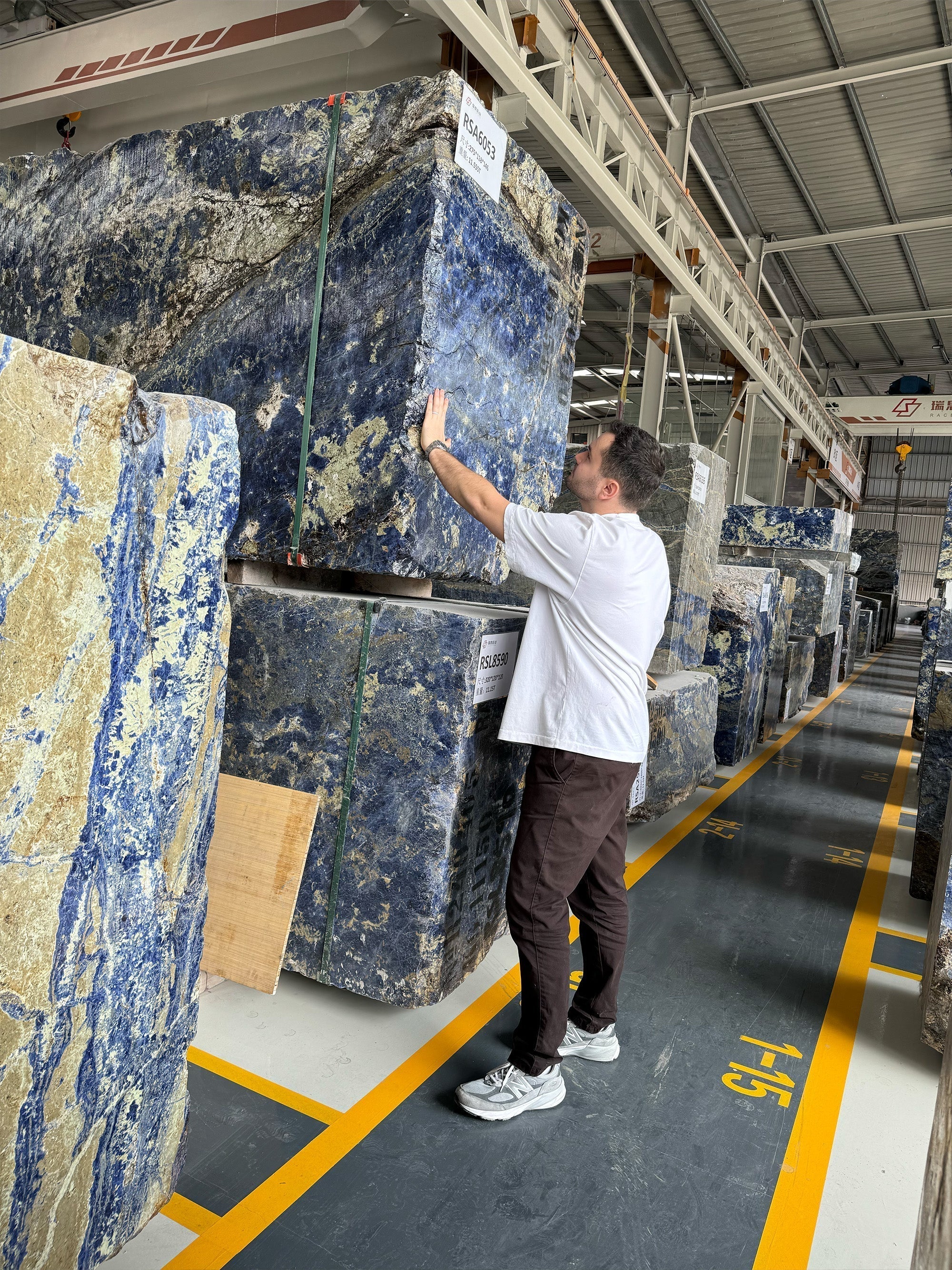 GustavDesign director inspecting a raw mountain block at the quarry to ensure quality for a direct-to-project commission.