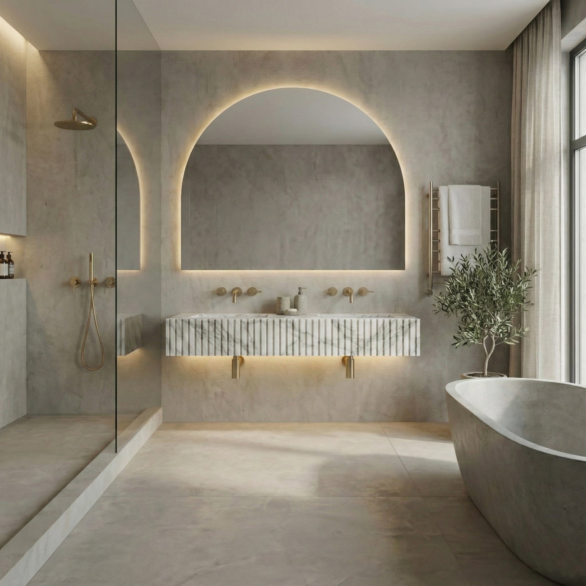 Mediterranean minimal bathroom featuring a floating Arabescato marble fluted sink, large backlit arched mirror, and textured concrete walls.