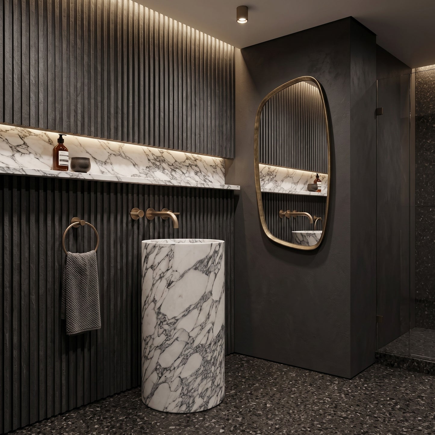 Freestanding Arabescato marble round pedestal basin in a moody luxury bathroom featuring charcoal fluted wall paneling, matching marble shelf, and organic brass mirror.