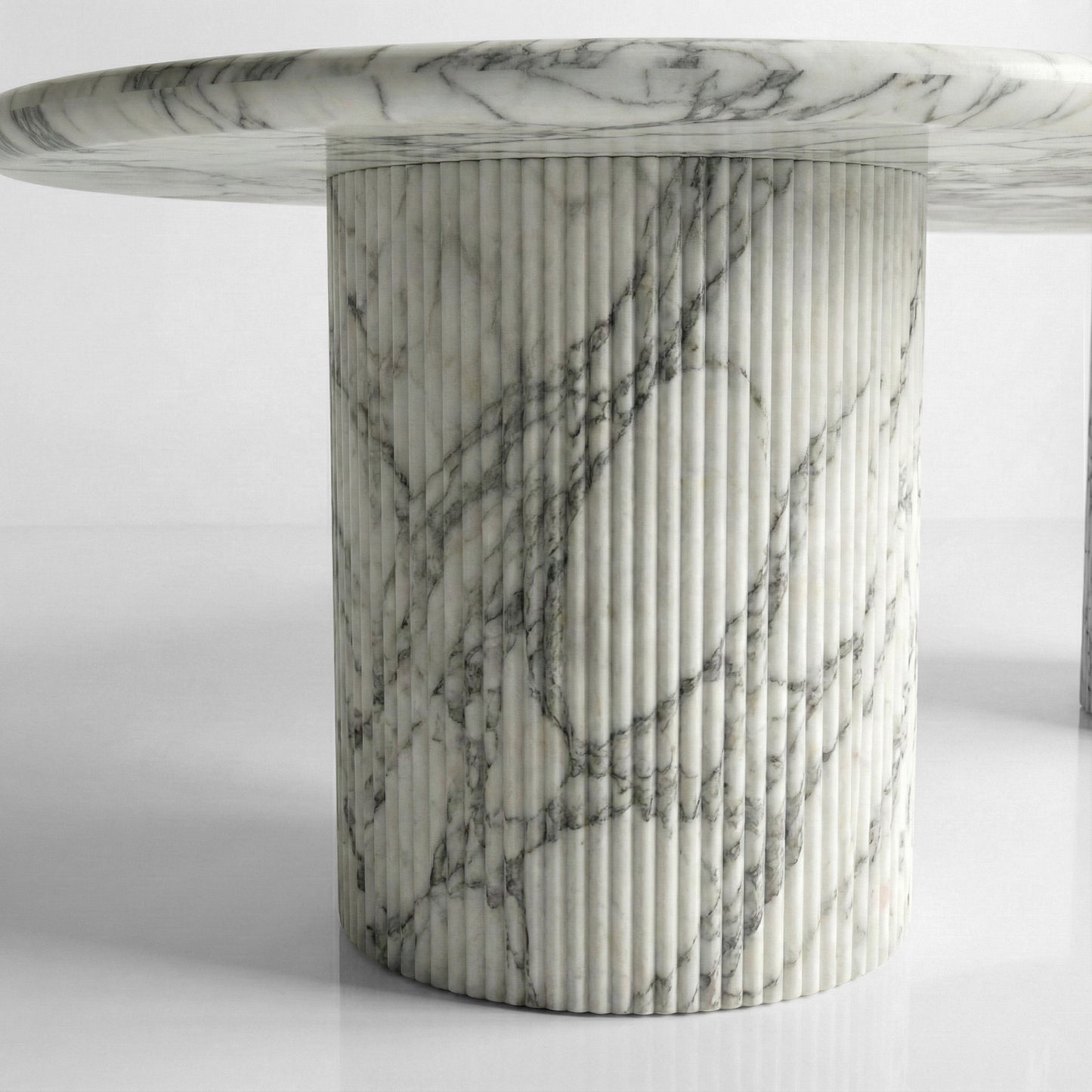 Detail shot of a fluted column table base crafted from Arabescato marble, showcasing the vertical ribbed texture and dusty grey mineral patterns.