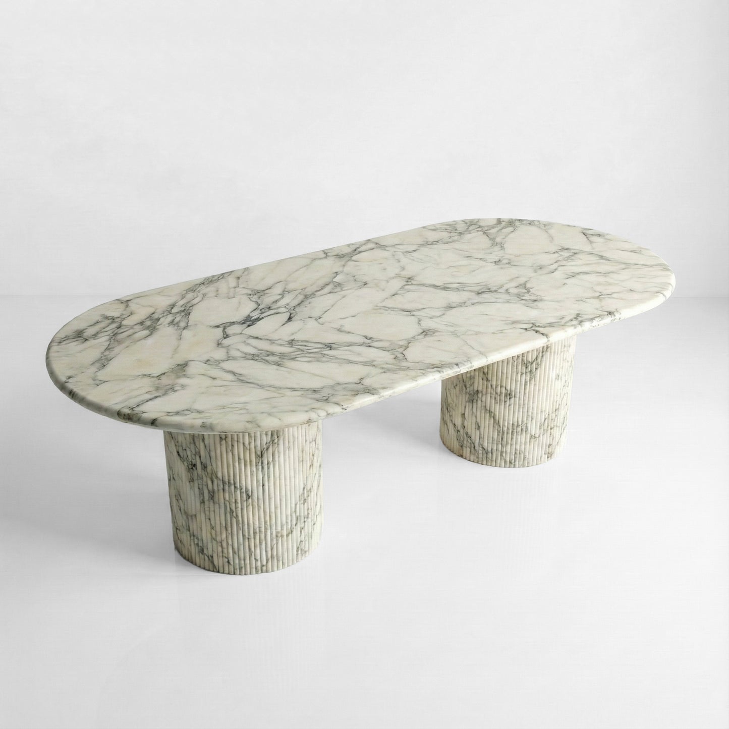 High-angle view of a large oval Arabescato marble dining table, displaying the stone's characteristic egg-shaped grey and white natural patterns.