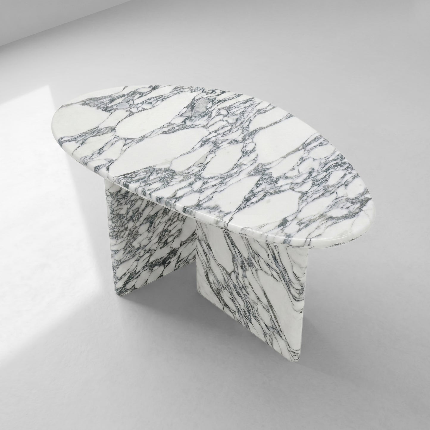 Top-down angled view of a sleek oval coffee table crafted from Arabescato marble, displaying the intricate natural stone patterns and contemporary sculptural design.