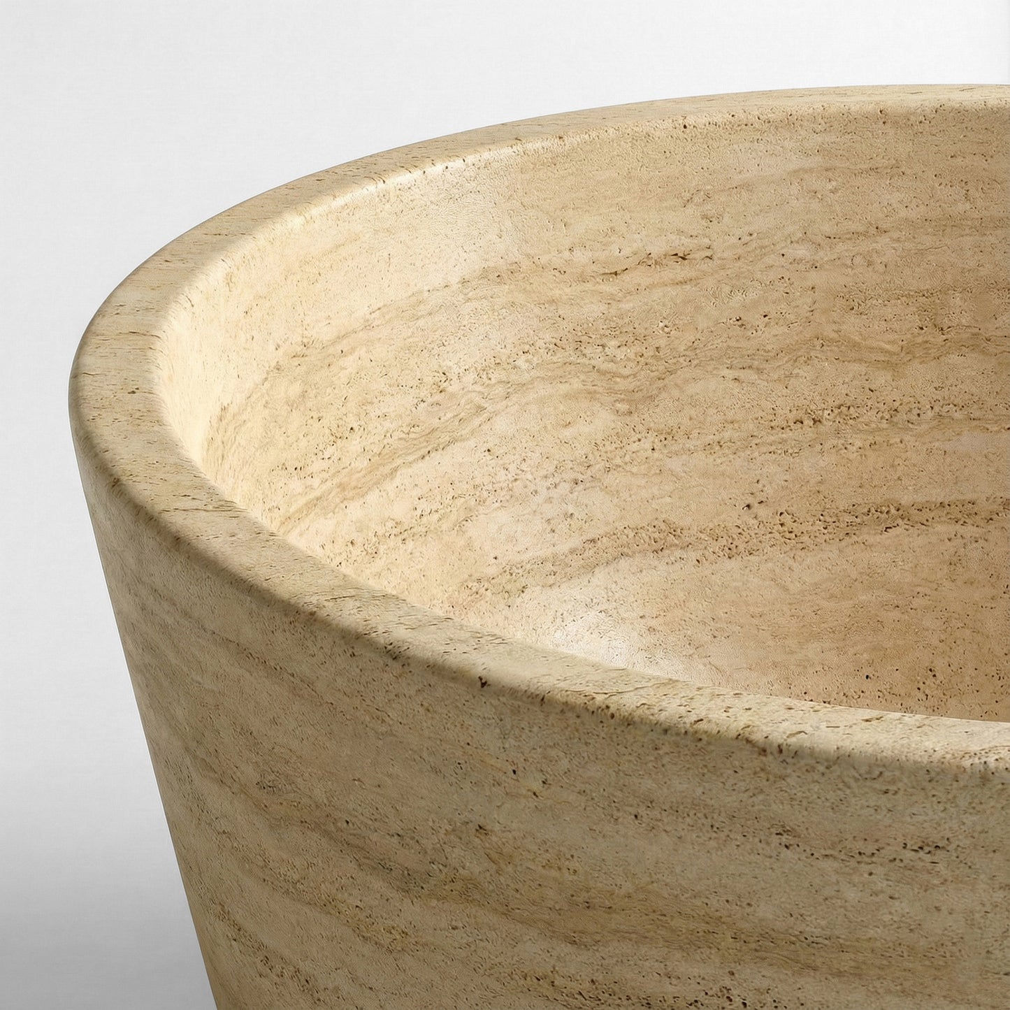 Close-up detail of a beige Travertine bathtub rim highlighting the natural porous texture and authentic cream-colored stone grain.