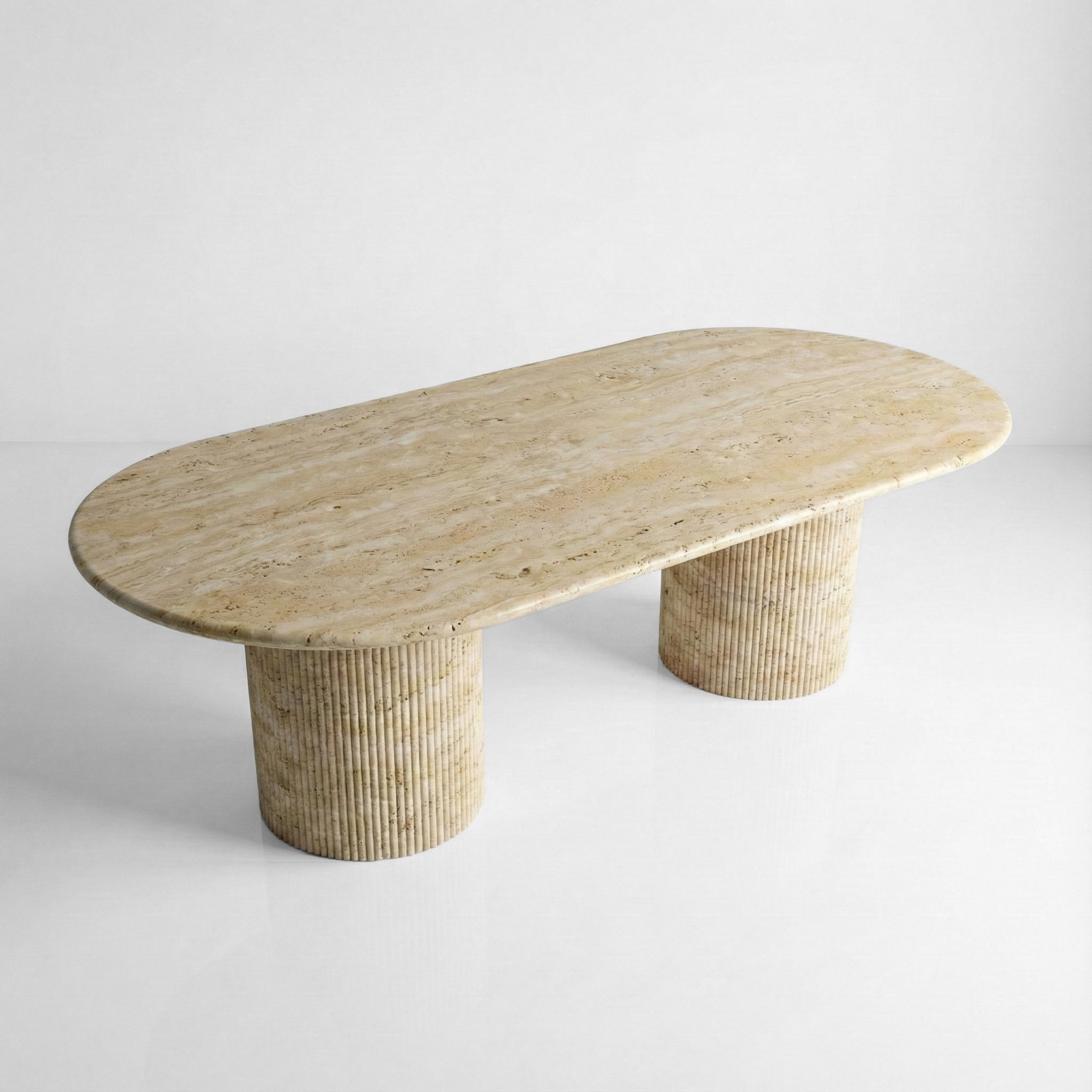 High-angle view of a large oval Beige Travertine dining table, featuring a smooth honed surface and subtle organic variations in the cream-colored stone.