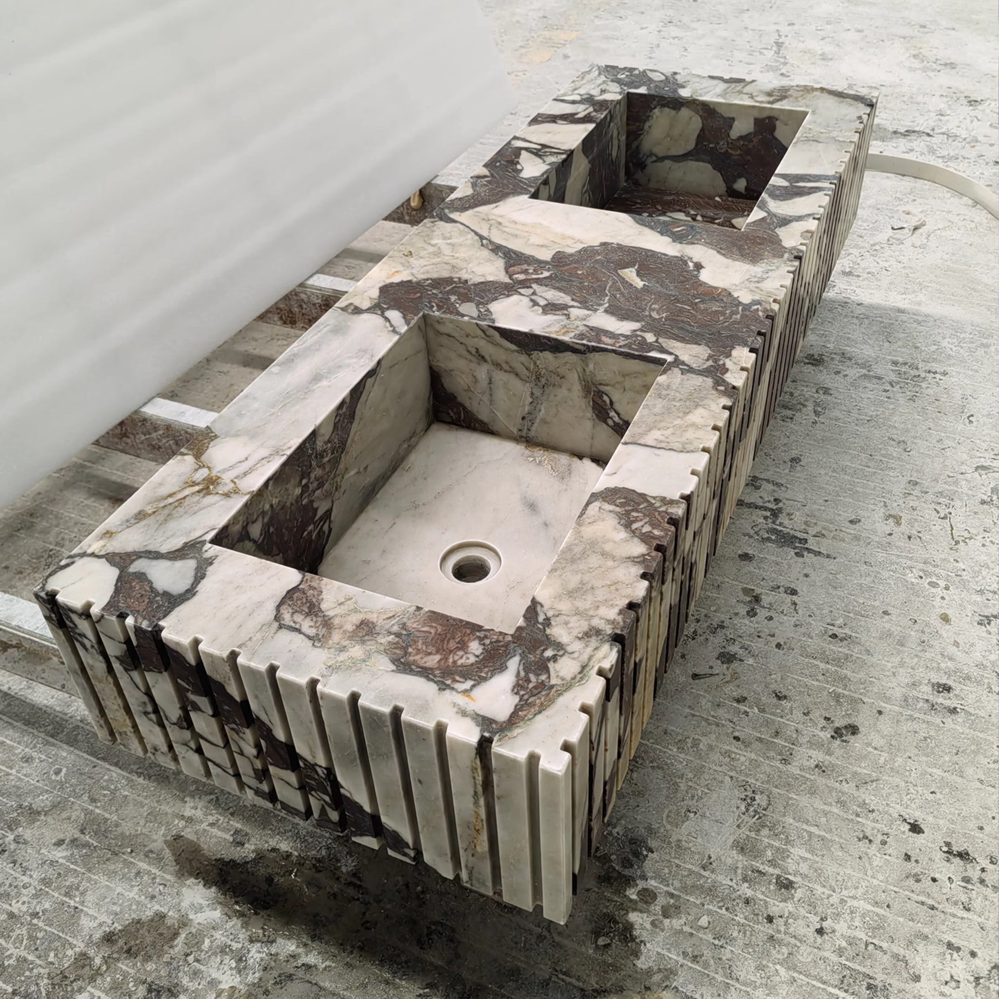 Bespoke integrated double vanity sink carved from exotic Calacatta Viola marble featuring a ribbed apron front design.