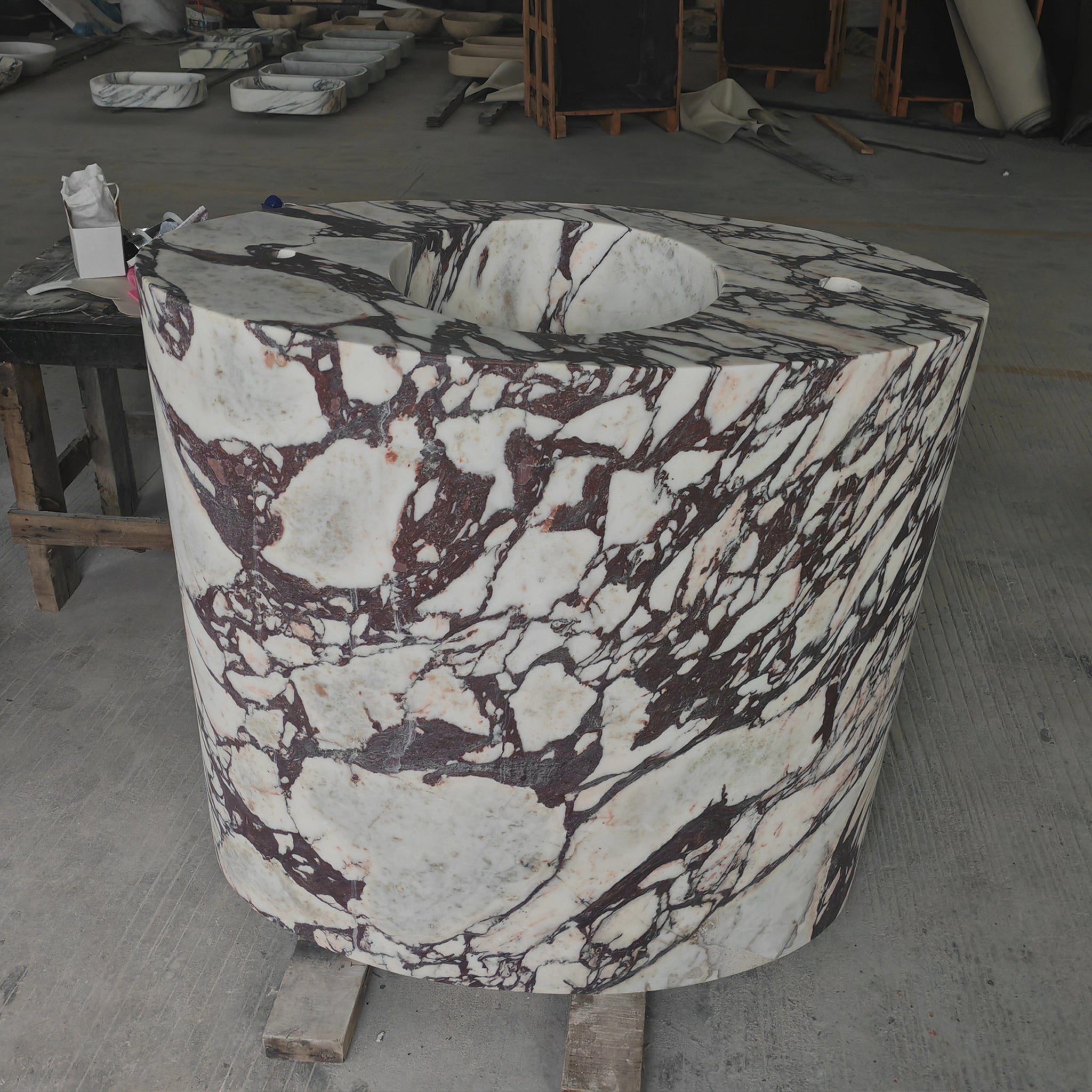 Solid block freestanding cylindrical washbasin carved from Calacatta Viola marble with dramatic purple veining.
