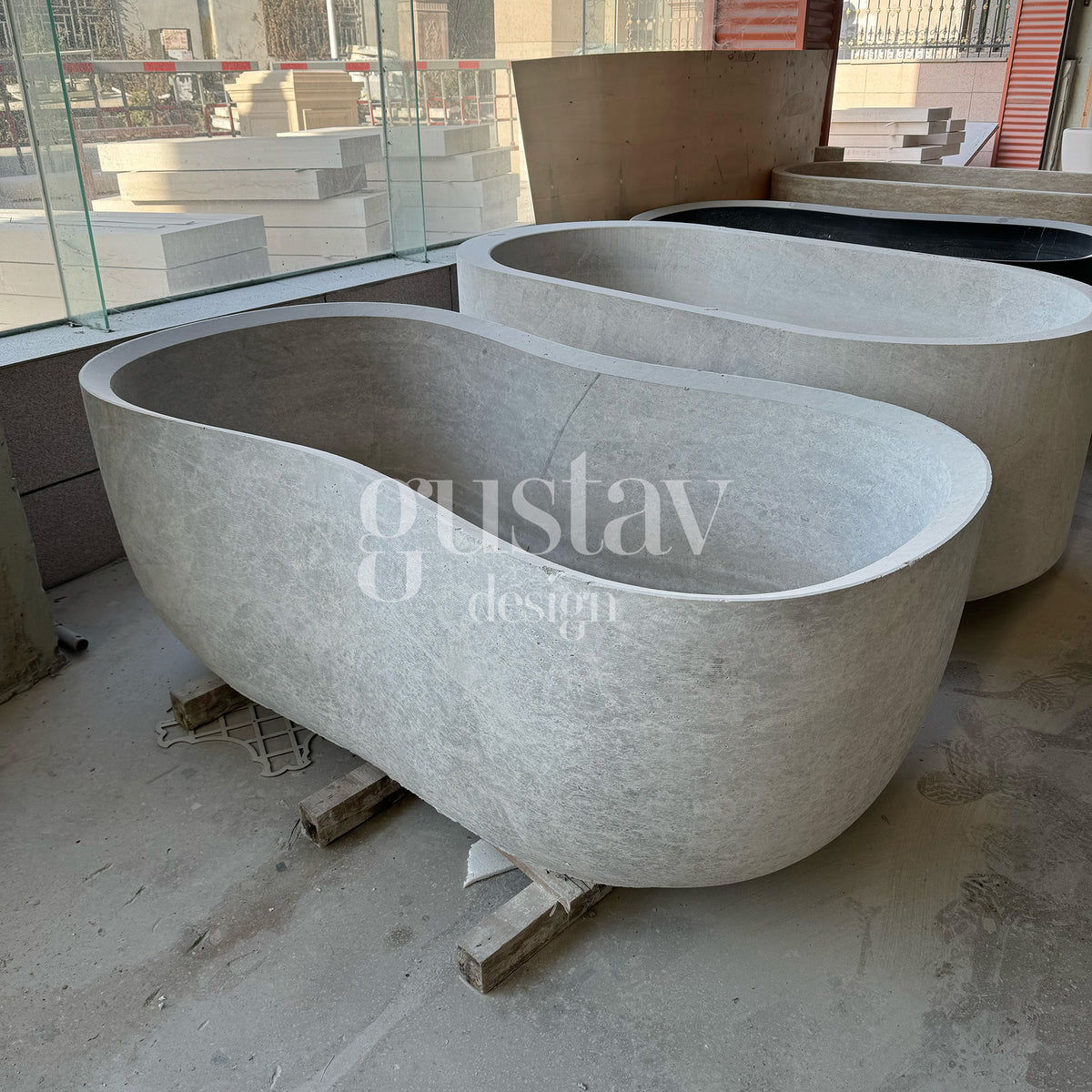 Two solid stone oval bathtubs in the final stages of fabrication, highlighting GustavDesign's capability in carving large-scale bespoke marble soaking tubs from single blocks.
