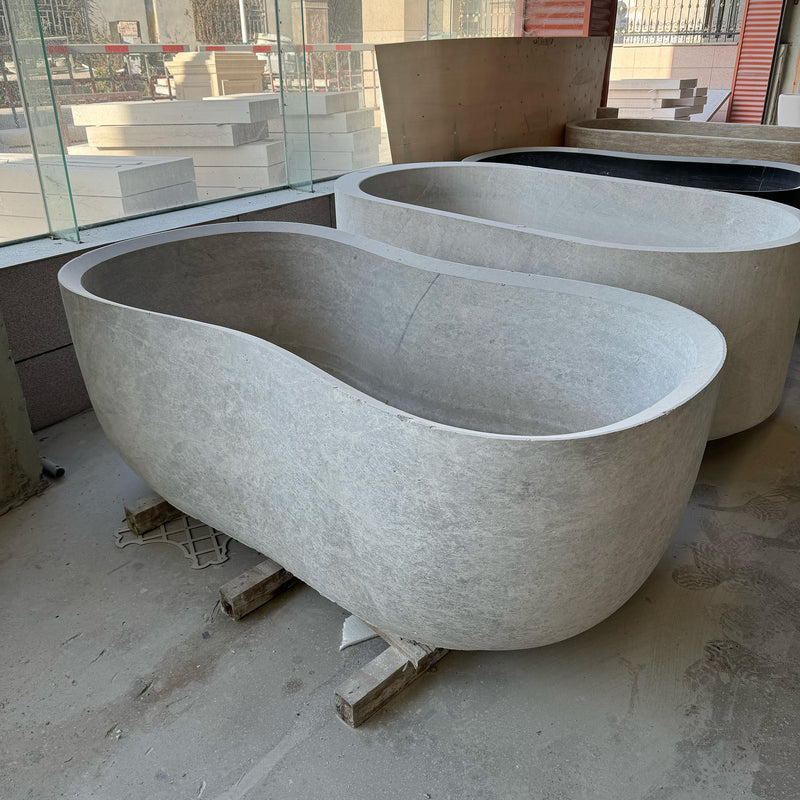 Two solid stone oval bathtubs in the final stages of fabrication, highlighting GustavDesign's capability in carving large-scale bespoke marble soaking tubs from single blocks.