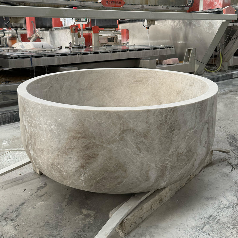 A massive circular Taj Mahal marble bathtub being carved in the workshop, showcasing the industrial stone fabrication scale and luxury bathroom customization available at GustavDesign.