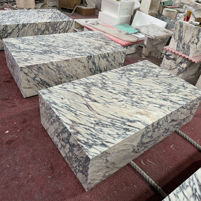 Large-scale Calacatta Viola marble plinth coffee tables with bold purple veining, handcrafted and ready for shipping in the GustavDesign workshop.
