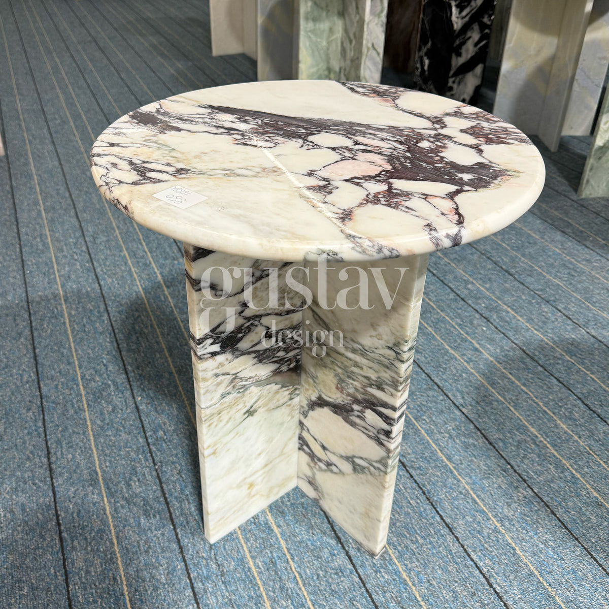 A round Calacatta Viola side table featuring a polished top and architectural cross-base, demonstrating the high-quality bespoke marble furniture craftsmanship of GustavDesign.