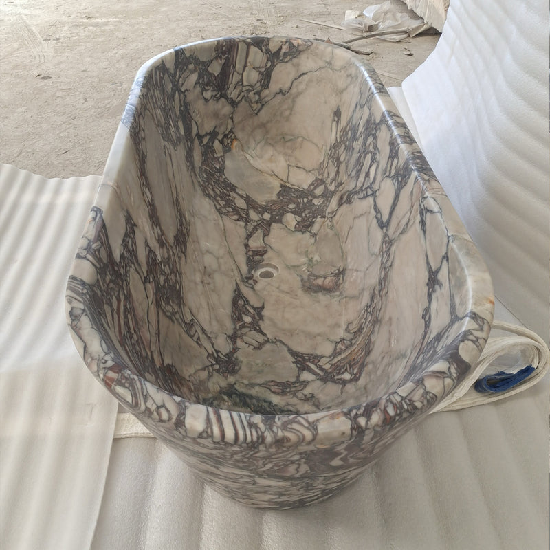 Top-down view of a bespoke Calacatta Viola marble bathtub in the workshop, showing the seamless solid stone rim and interior carving.