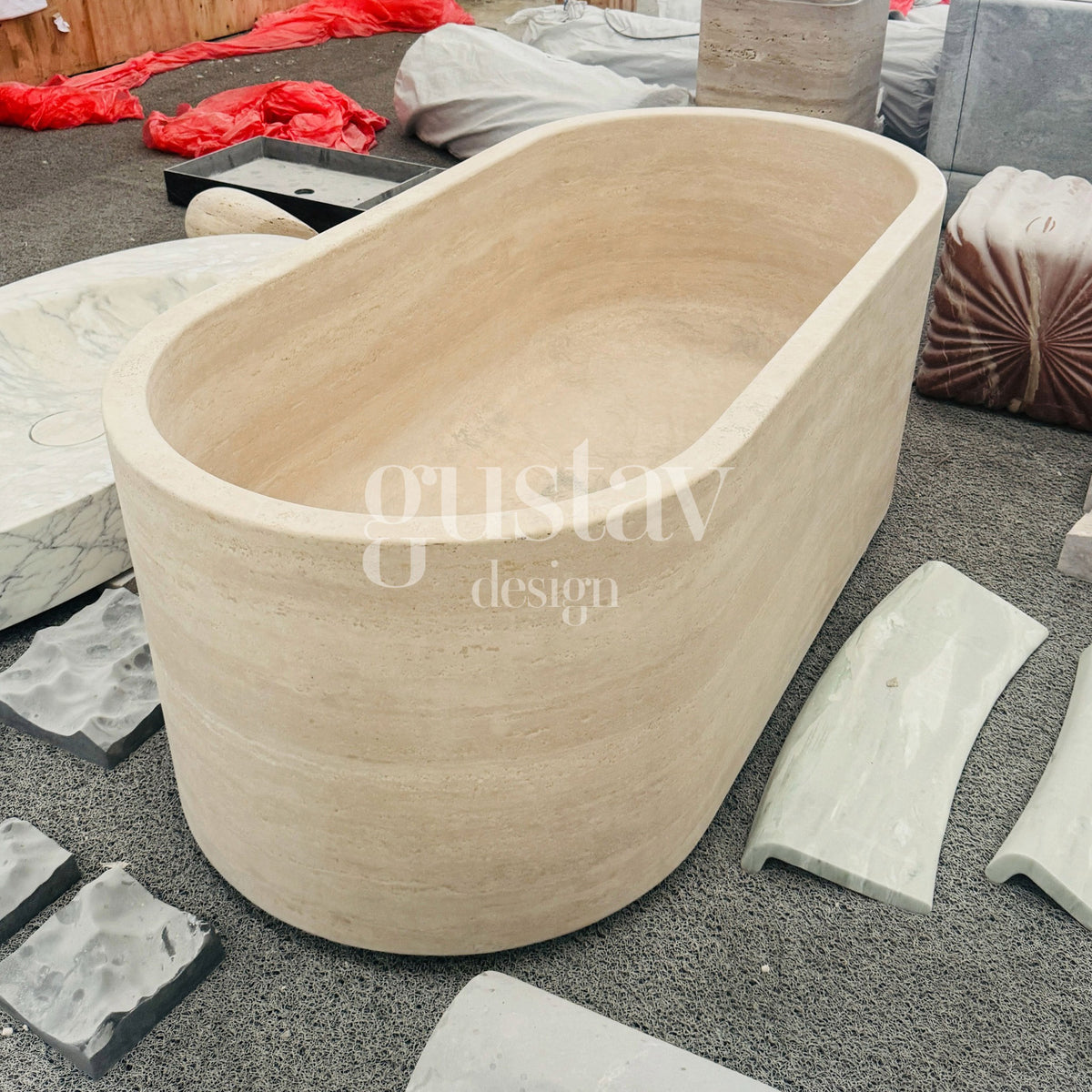 Elevated workshop view of an oval freestanding Beige Travertine stone bathtub featuring honed curved rims, natural horizontal sedimentary strata, and seamless natural stone craftsmanship.