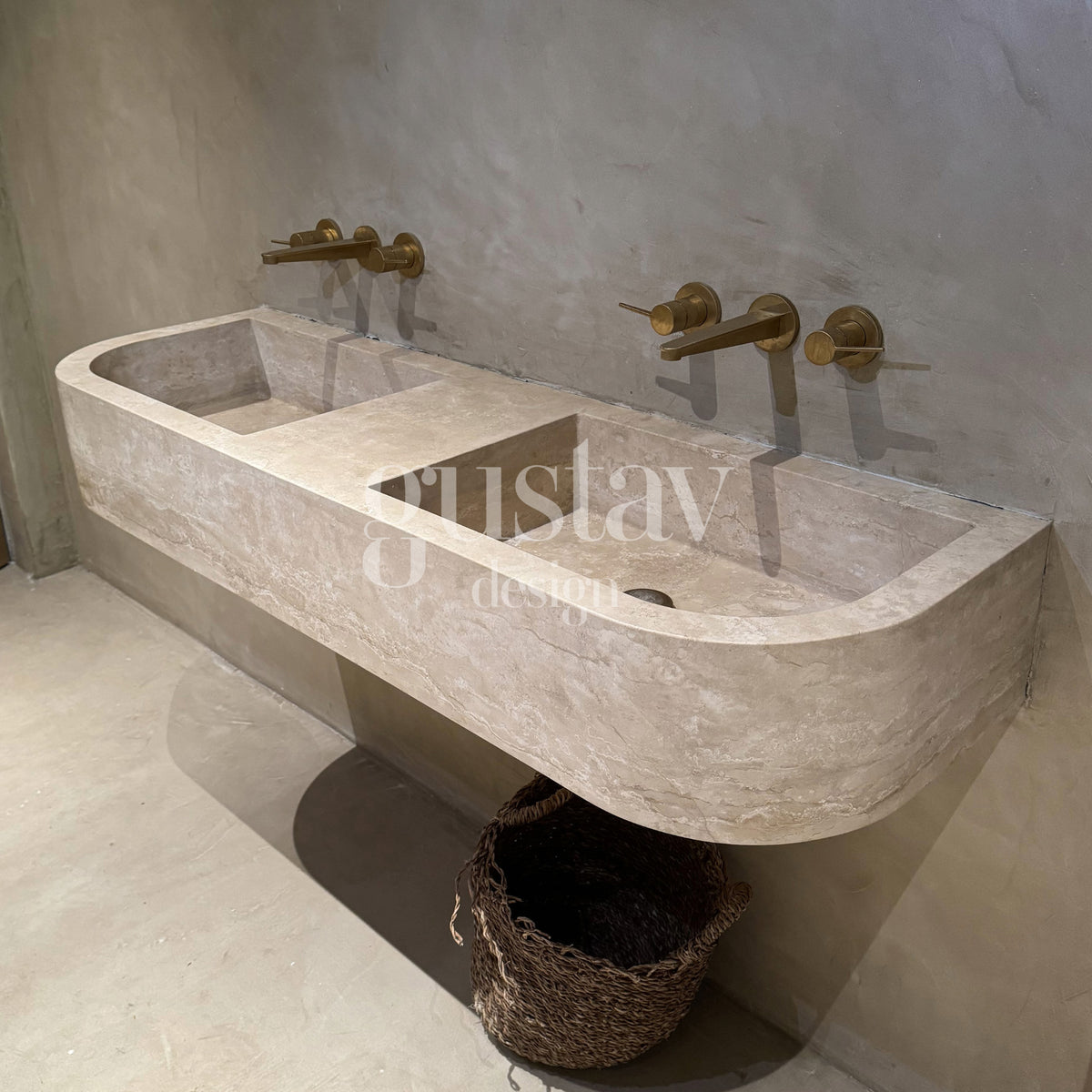 Wall-mounted double floating vanity sink in Beige Travertine featuring curved bullnose end profiles, dual integrated wash basins, and wall-mounted brass tapware set against microcement walls.