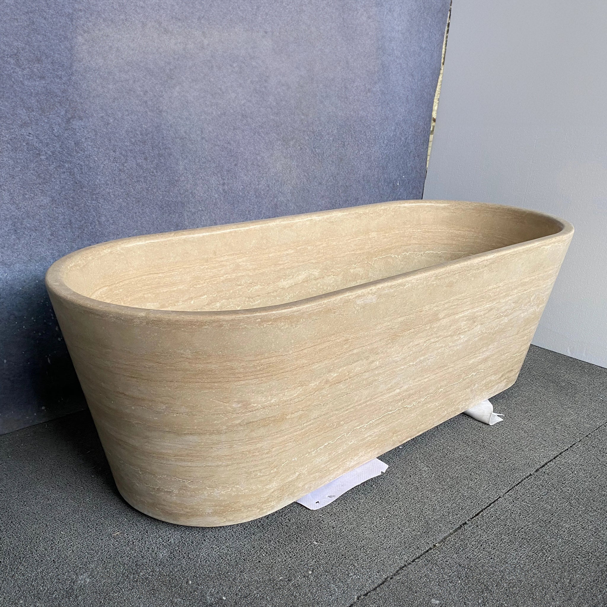 Completed bespoke beige travertine freestanding bathtub showcasing natural horizontal vein cut patterns, ready for shipping.
