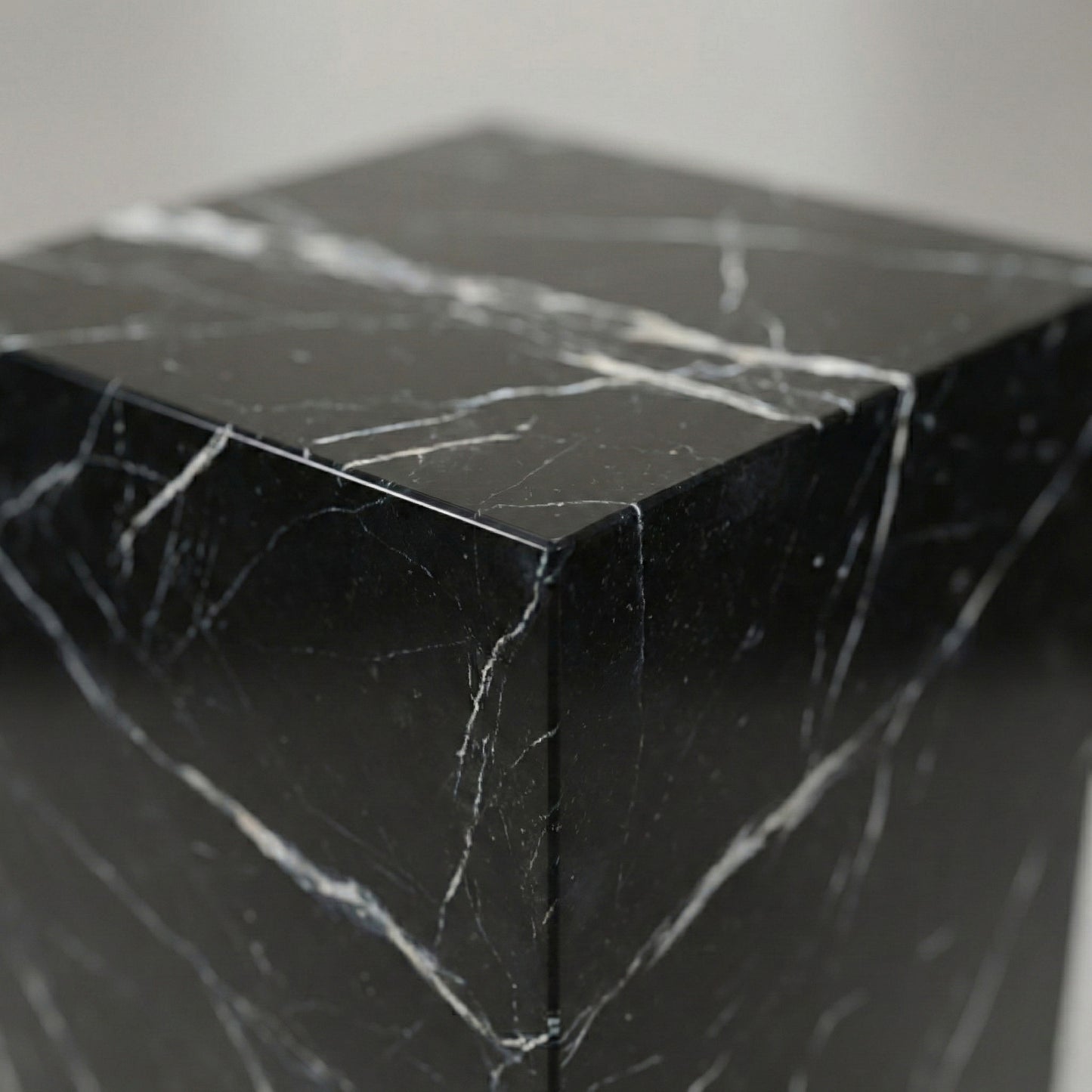 Close-up of a Nero Marquina marble stand showing precision mitered joints and hand-polished satin finish.