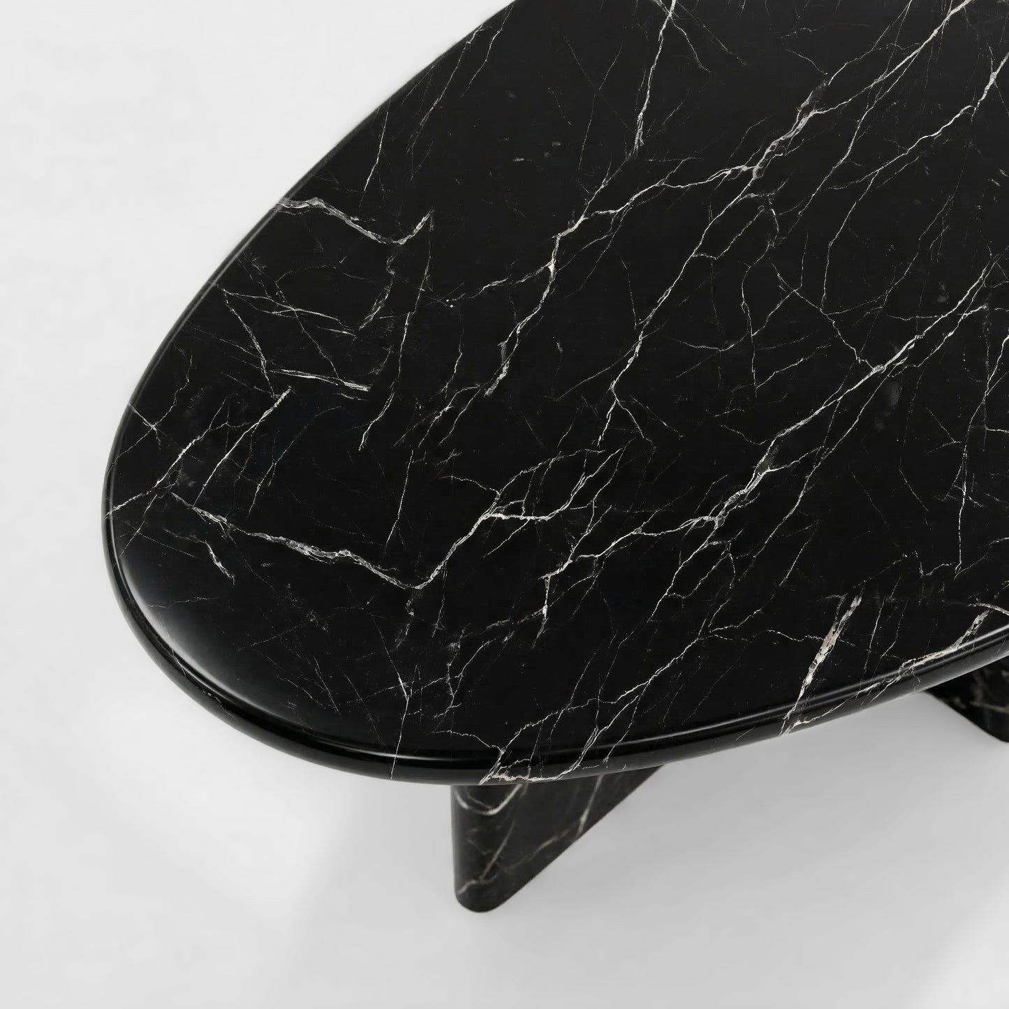 Side profile of a luxury Black Marquina marble coffee table featuring a sculptural two-leg base and a thick pebble-shaped top against a minimalist white background.