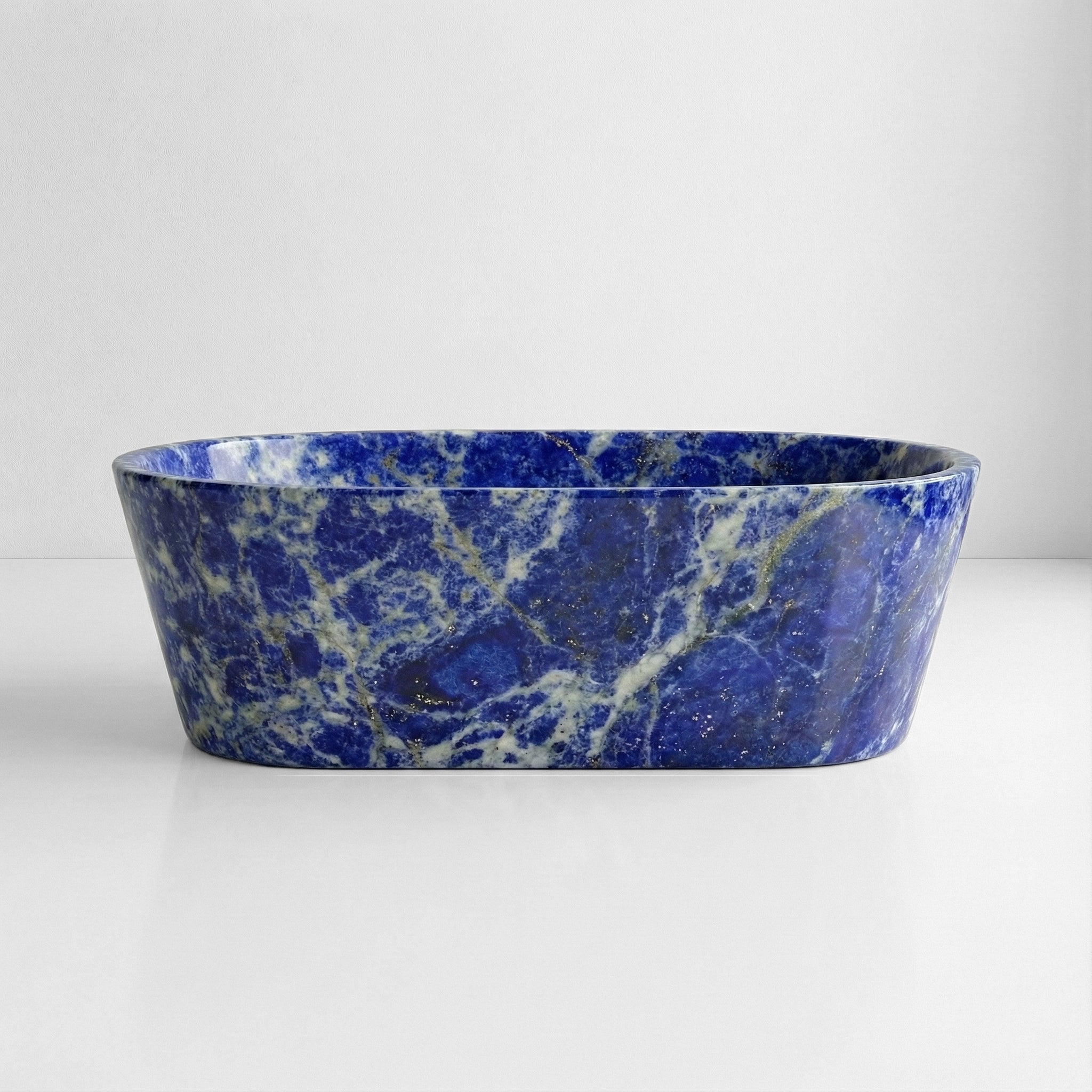 Front profile of a majestic Blue Sodalite stone bathtub featuring intense royal blue hues and a high-gloss polished finish typical of semi-precious masonry.