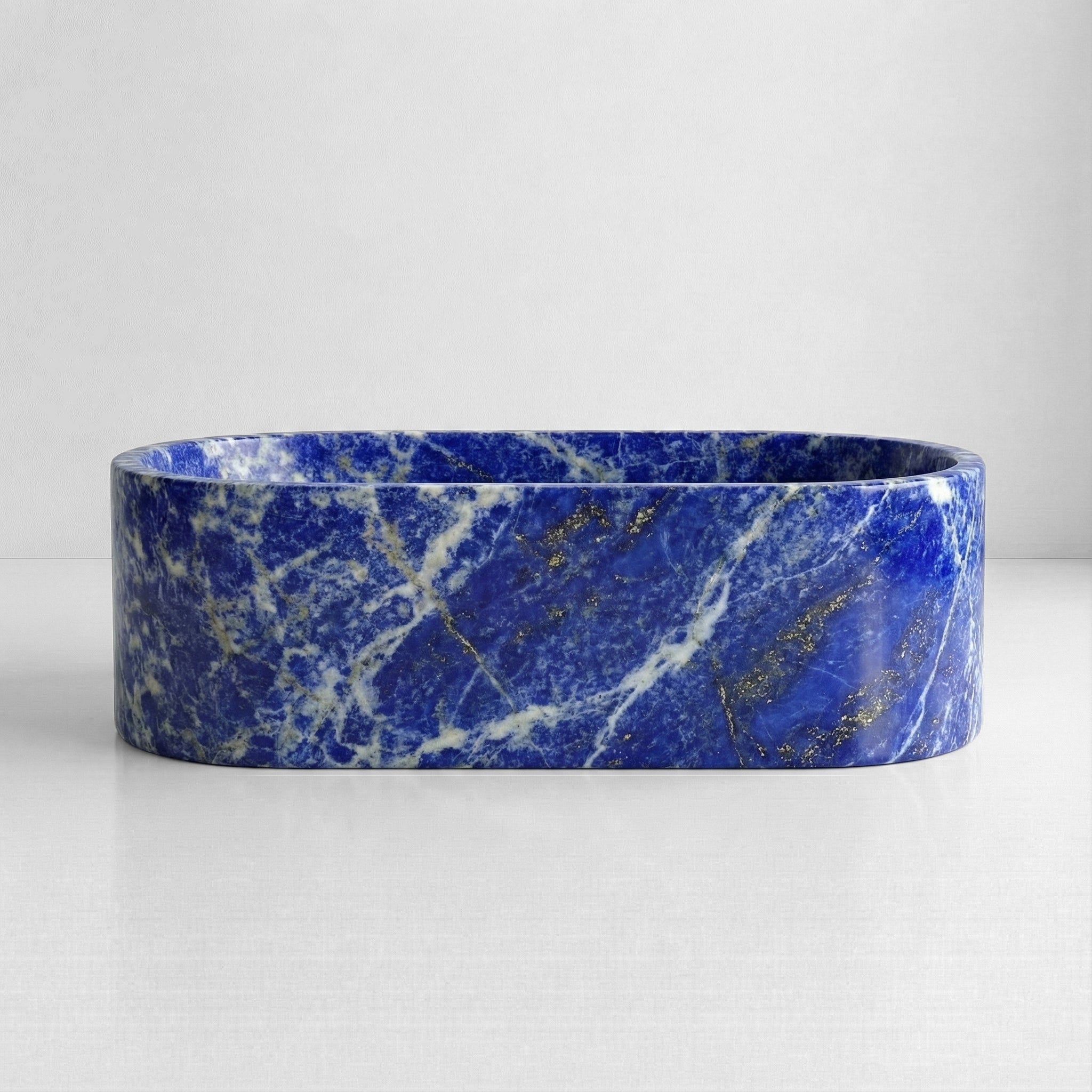 Front view of a freestanding oval Blue Sodalite tub, displaying a polished finish with intense indigo blue and white calcite veining.