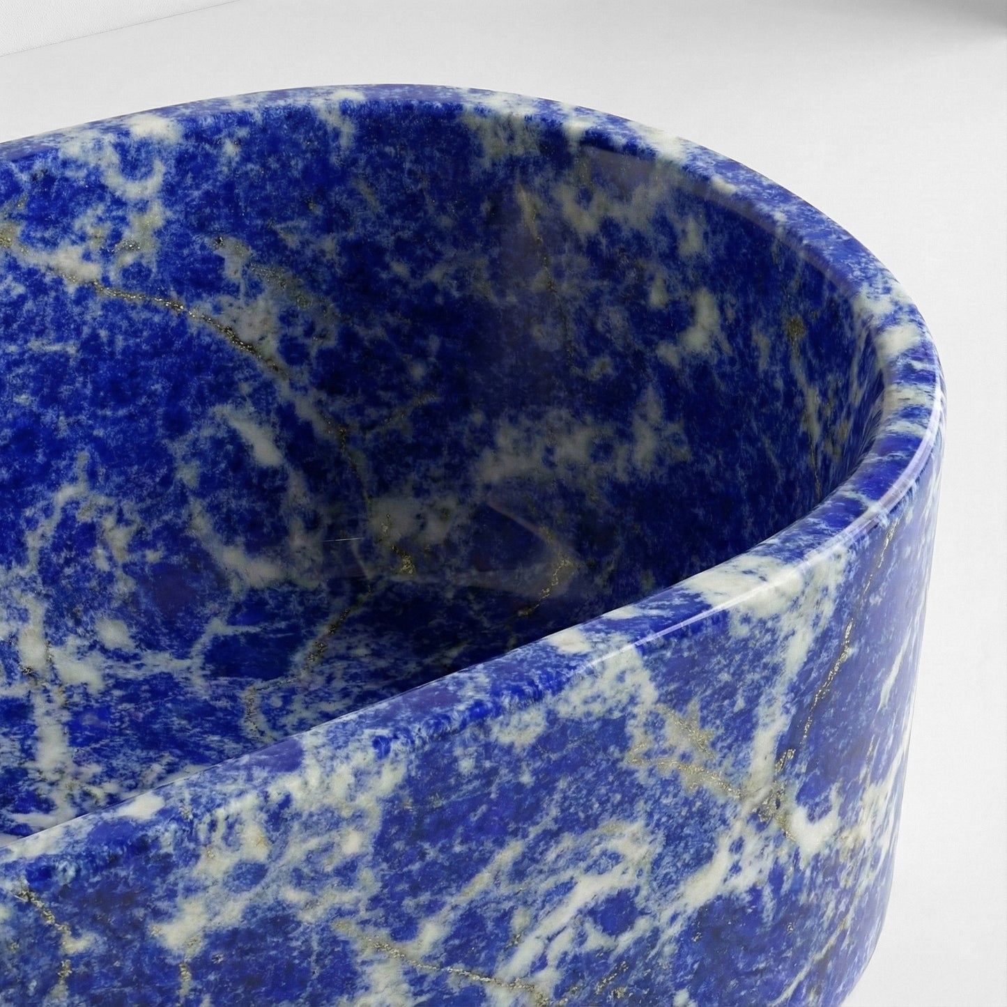 Close-up detail of a Blue Sodalite bathtub rim, revealing the complex texture of blue lazurite, white calcite, and metallic pyrite inclusions.