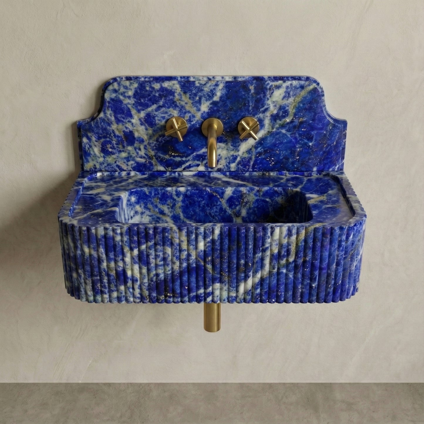 Front profile of a wall-mounted Blue Sodalite gemstone washbasin featuring a decorative high backsplash, vertical ribbed texture, and deep royal blue stone with gold pyrite inclusions.