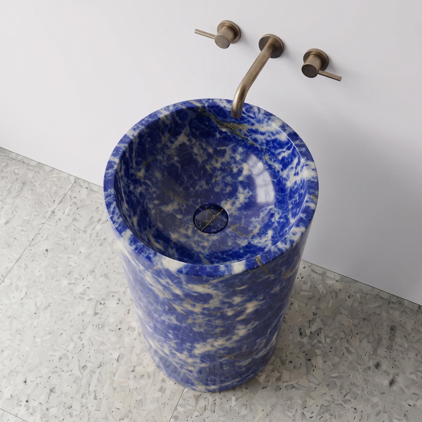 High-angle top view of a solid Blue Sodalite cylindrical pedestal sink showing vivid cobalt veining and matching carved stone drain cover.