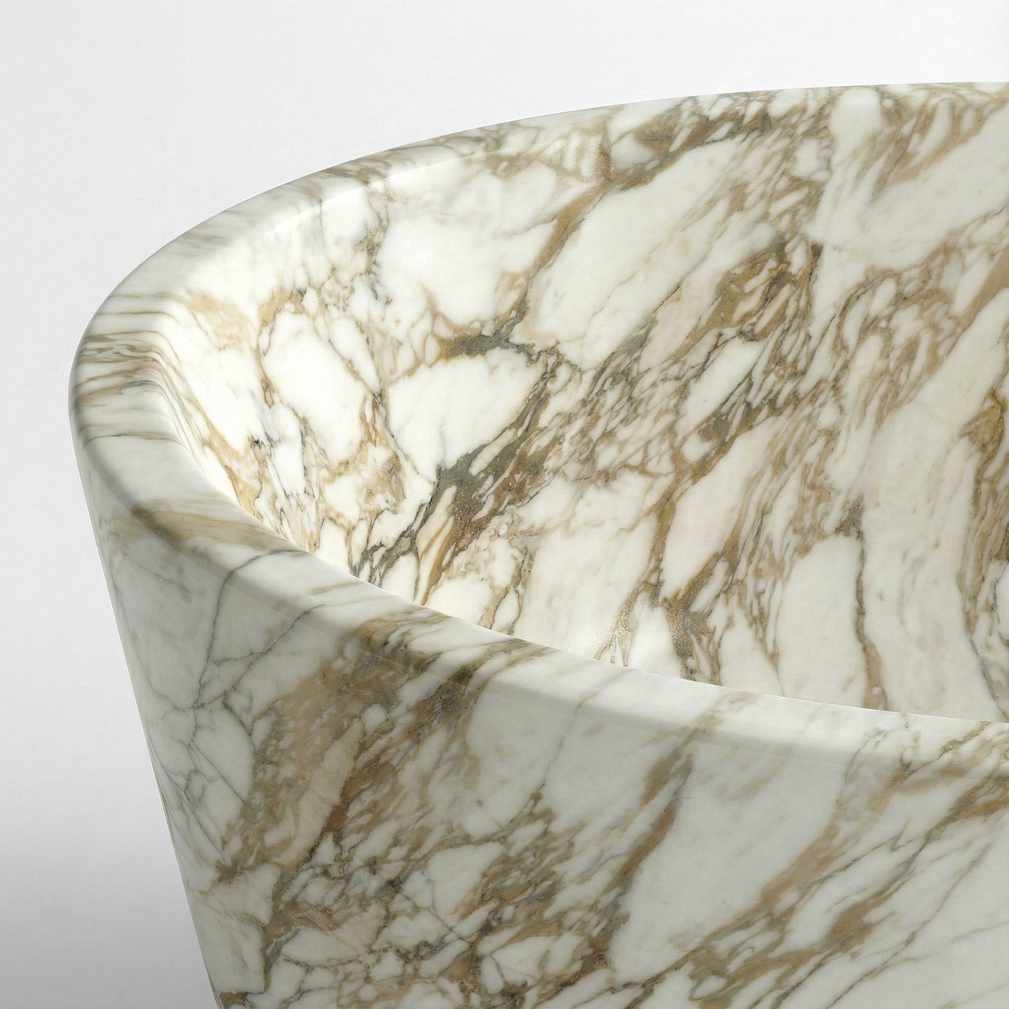 A close-up detail of the smooth, thick rim and intricate gold veining of a polished Calacatta Gold marble bathtub.