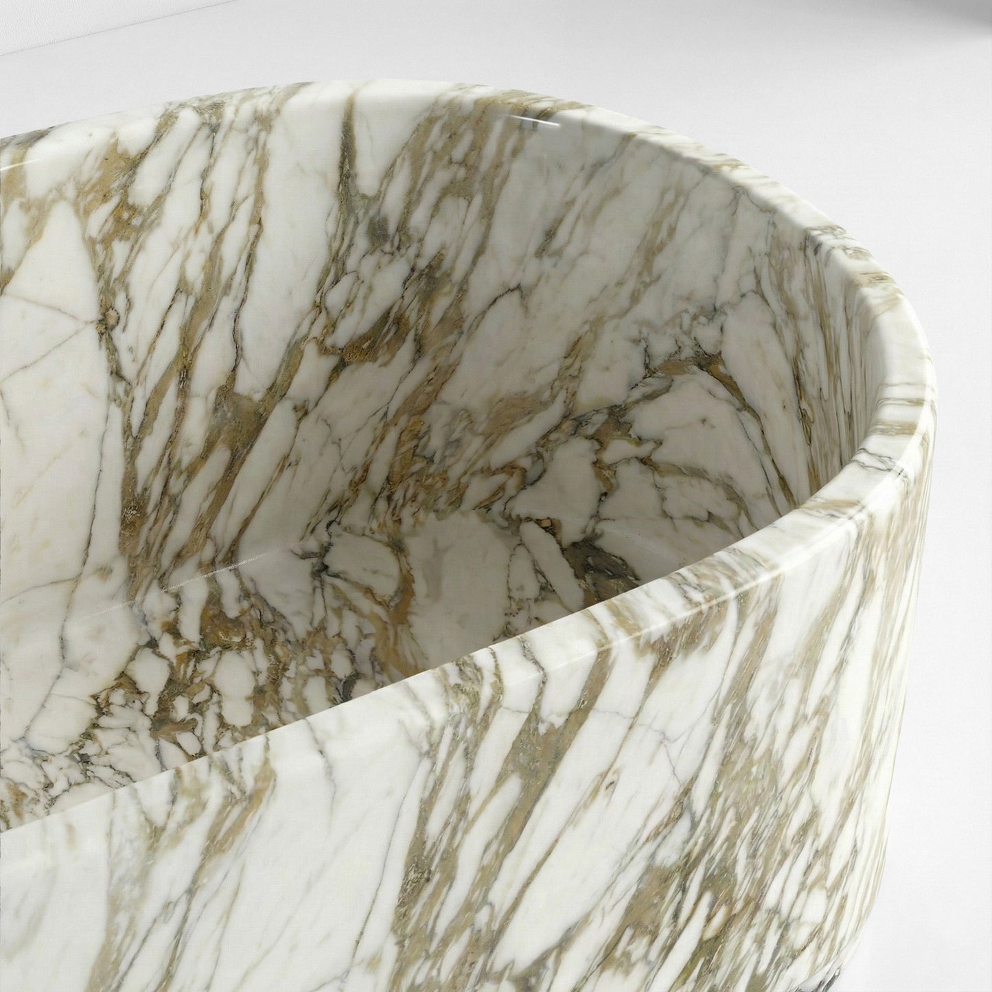 A detailed close-up of the interior wall and rim of a Calacatta Gold marble bathtub, showcasing the polished finish and unique stone texture.