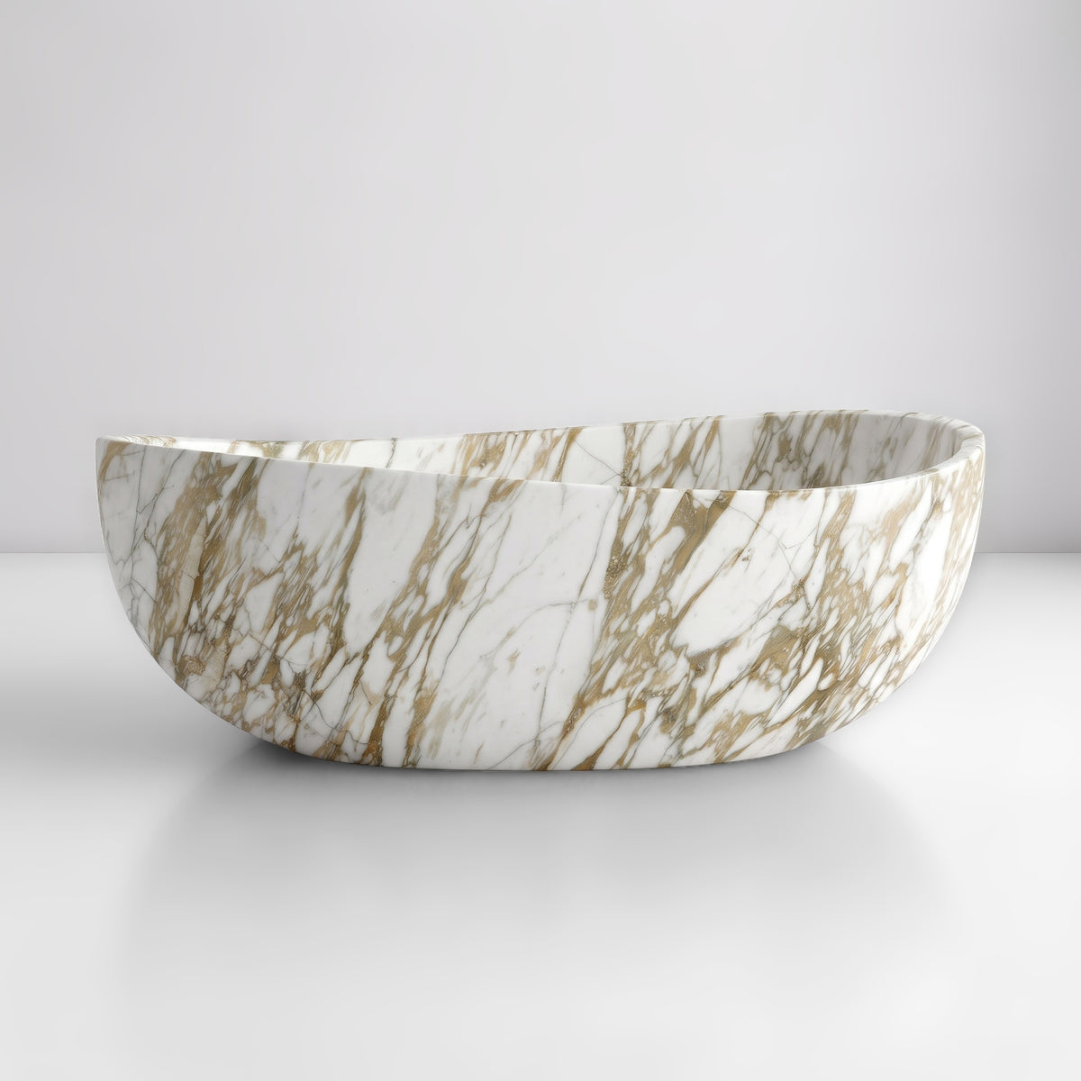 Front studio view of the freestanding Calacatta Gold marble wave bathtub, showcasing the organic dipping rim silhouette and warm honey-gold and soft grey veining across the luminous white stone exterior.
