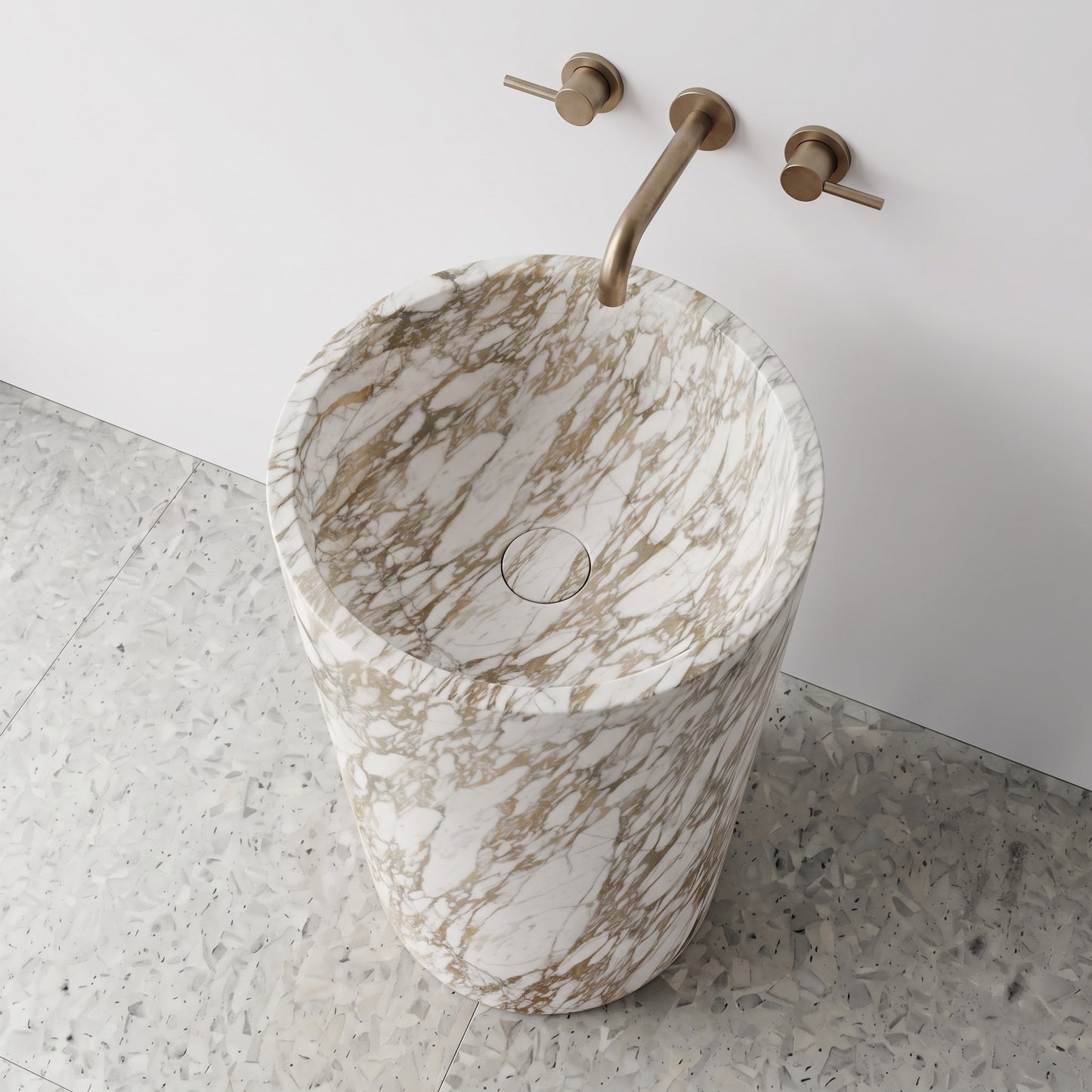 High-angle top view of a Calacatta Gold cylindrical marble pedestal sink highlighting honey-gold veining and matching integrated stone drain cap.
