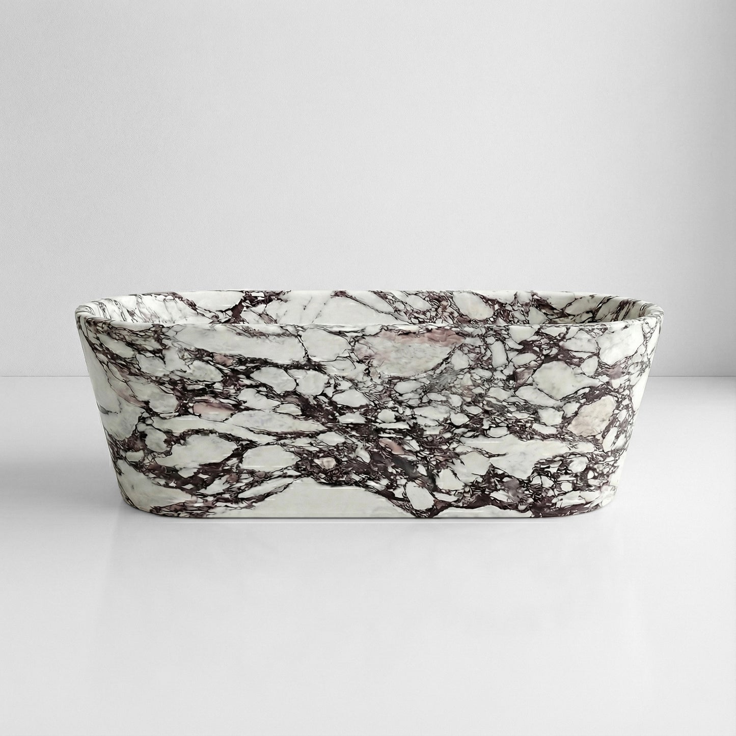 Front profile view of a luxury Calacatta Viola marble soaking tub featuring dramatic purple and white natural stone veining against a minimal background.