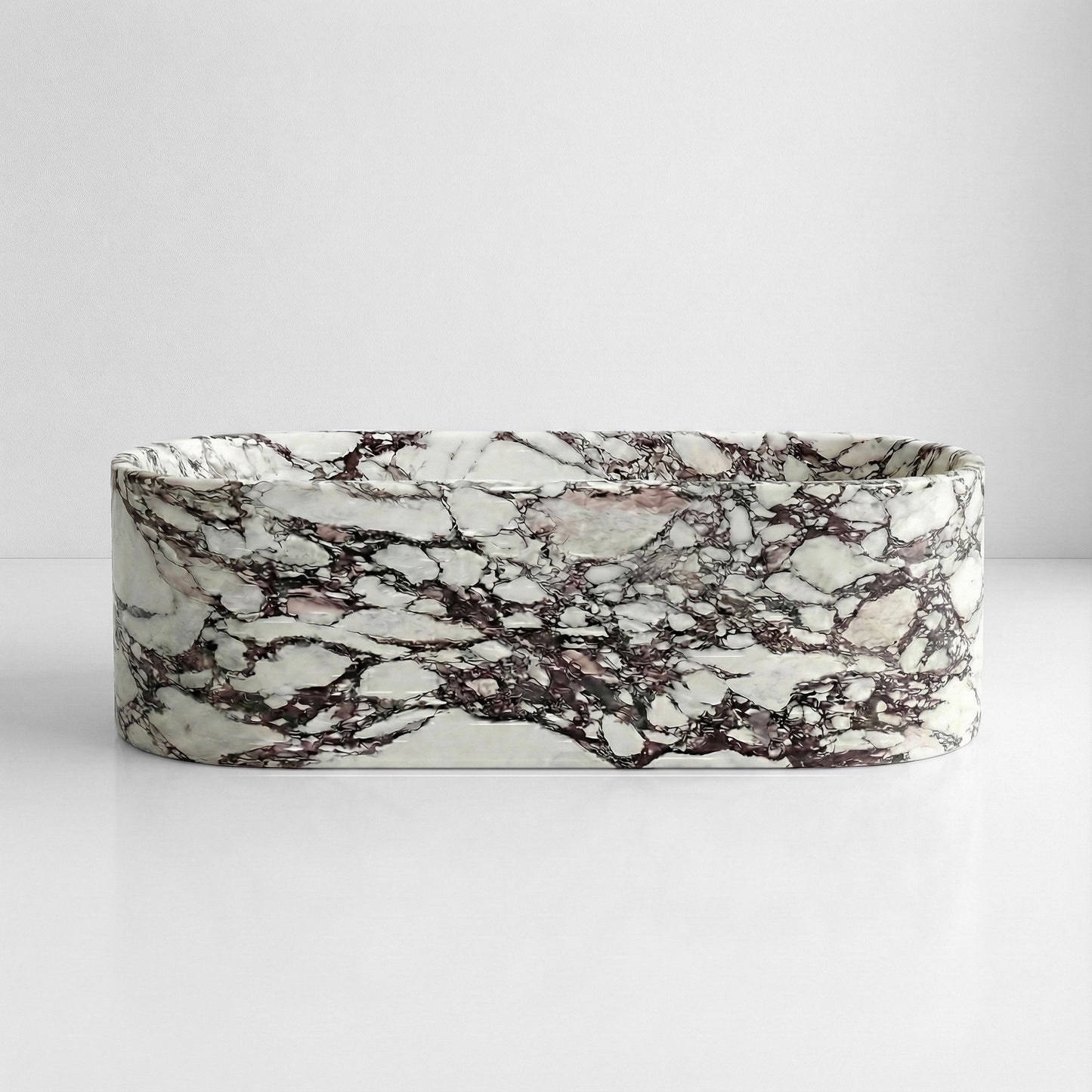 Front view of a freestanding oval bathtub made from polished Calacatta Viola marble with dramatic purple veining.