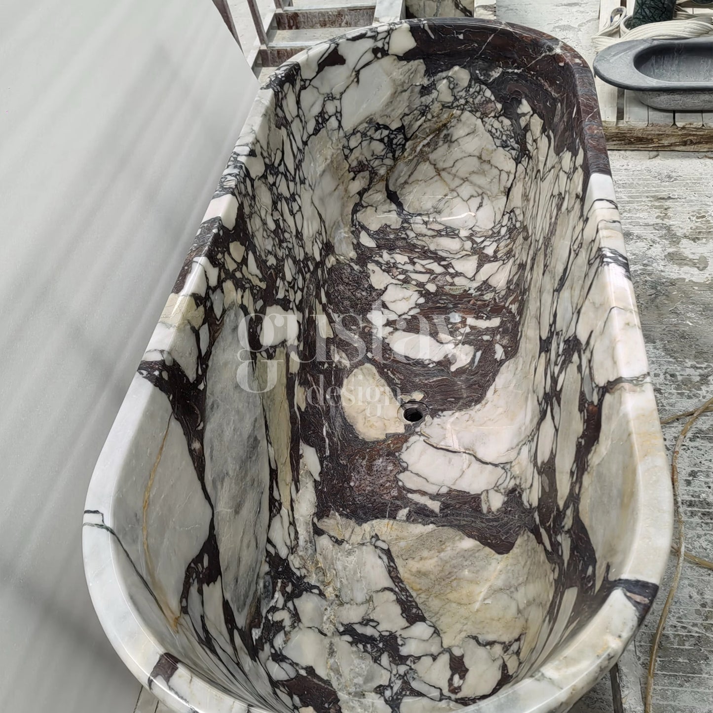 Perspective view of a massive Calacatta Viola Extra marble bathtub, emphasizing its heavy gauge stone construction and luxurious, deep soaking depth.