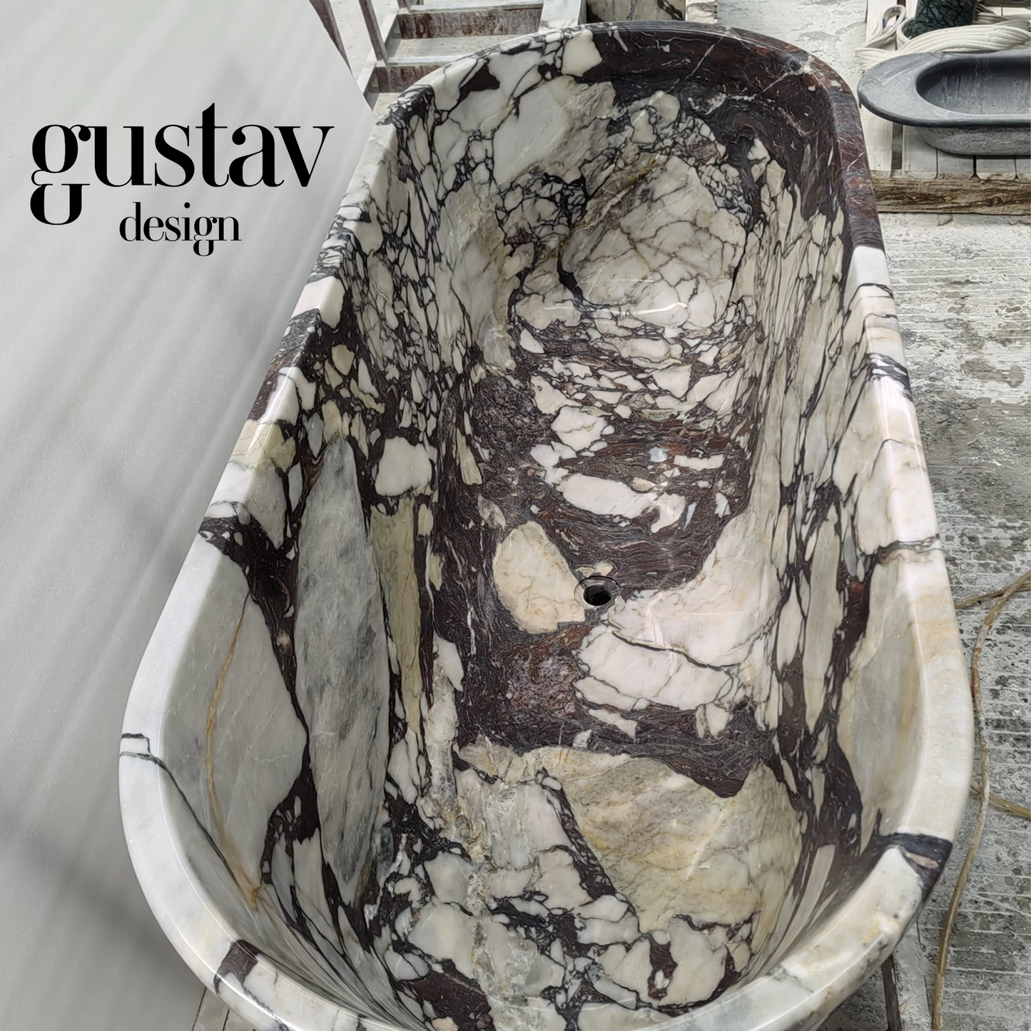 High-angle view of a custom Calacatta Viola Extra marble bathtub in production, revealing the deep, seamless soaking interior and dramatic natural stone patterns.