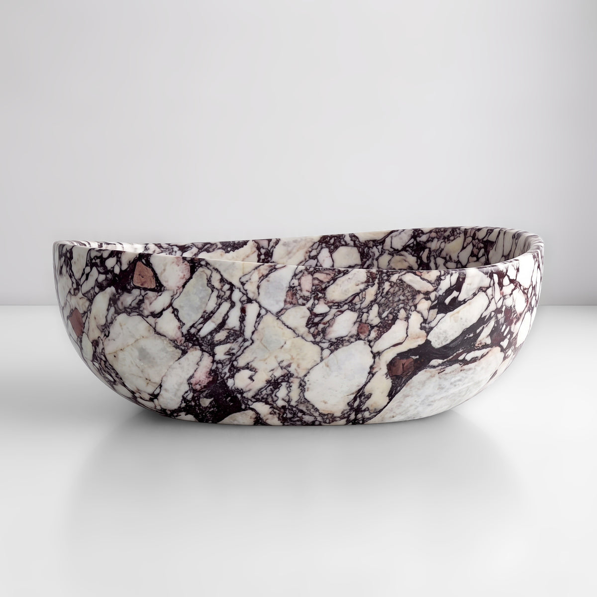 Front studio view of the freestanding Calacatta Viola marble wave bathtub, showcasing the organic dipping rim silhouette and dramatic burgundy, aubergine, and wine-red breccia veining across the creamy-white stone exterior.