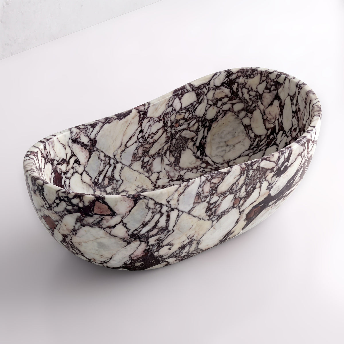 Elevated three-quarter perspective view of the Calacatta Viola marble wave soaking tub, highlighting the asymmetrical undulating rim, seamless solid-carved interior, and bold cabernet breccia veining.