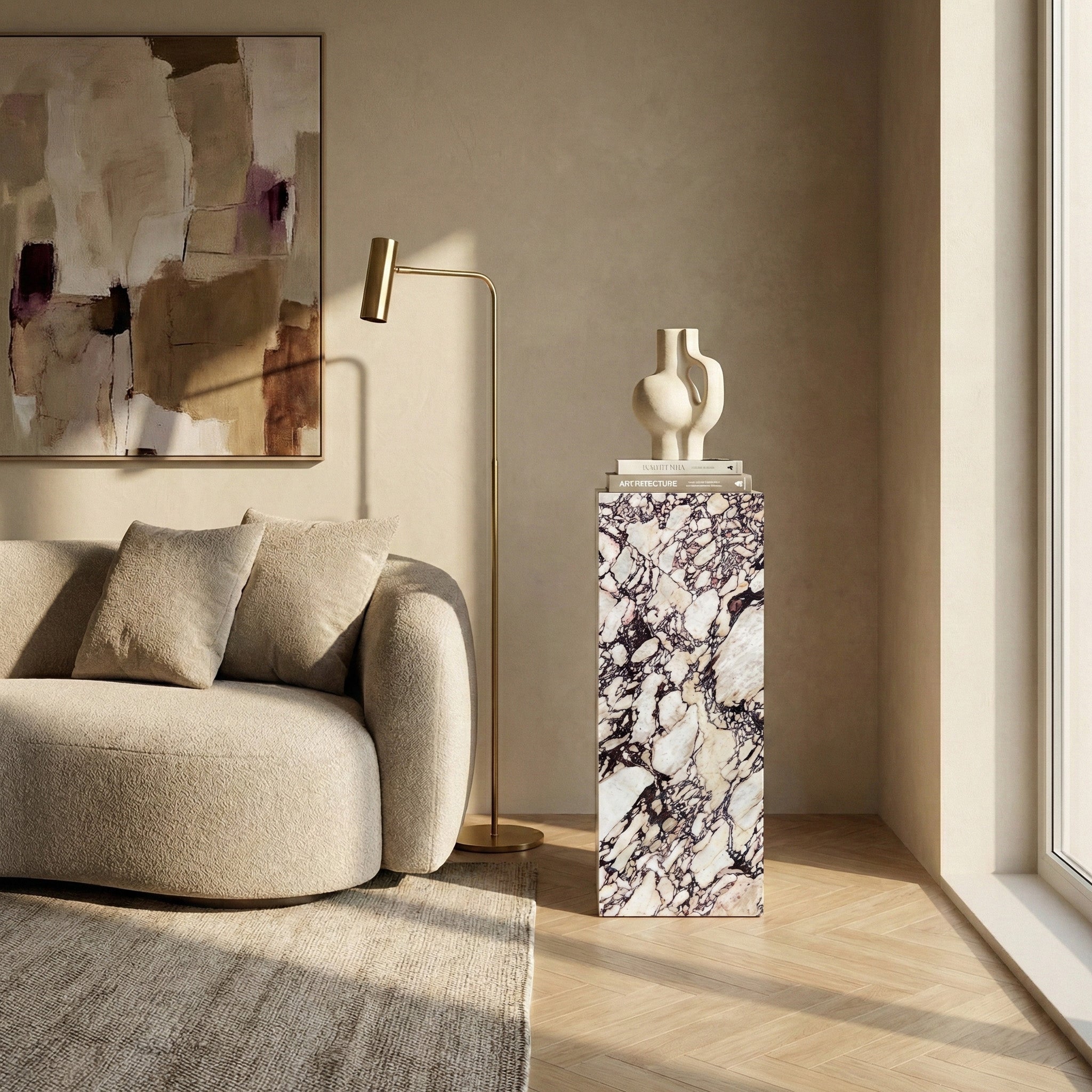A sunlit, modern living room featuring a tall Calacatta Viola marble pedestal used as a display stand for a sculptural white vase, positioned next to a beige textured sofa and a gold floor lamp.