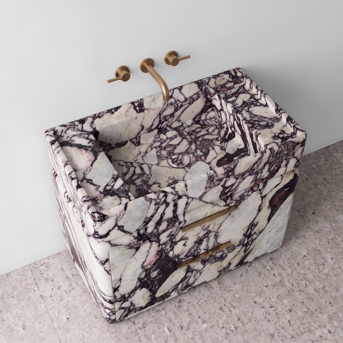 High-angle perspective view of the Calacatta Viola marble double-drawer vanity, highlighting the integrated stone trough sink with matching drain cover, raised border edge, rounded drawer corners, brushed brass linear pulls, and bold cabernet veining.