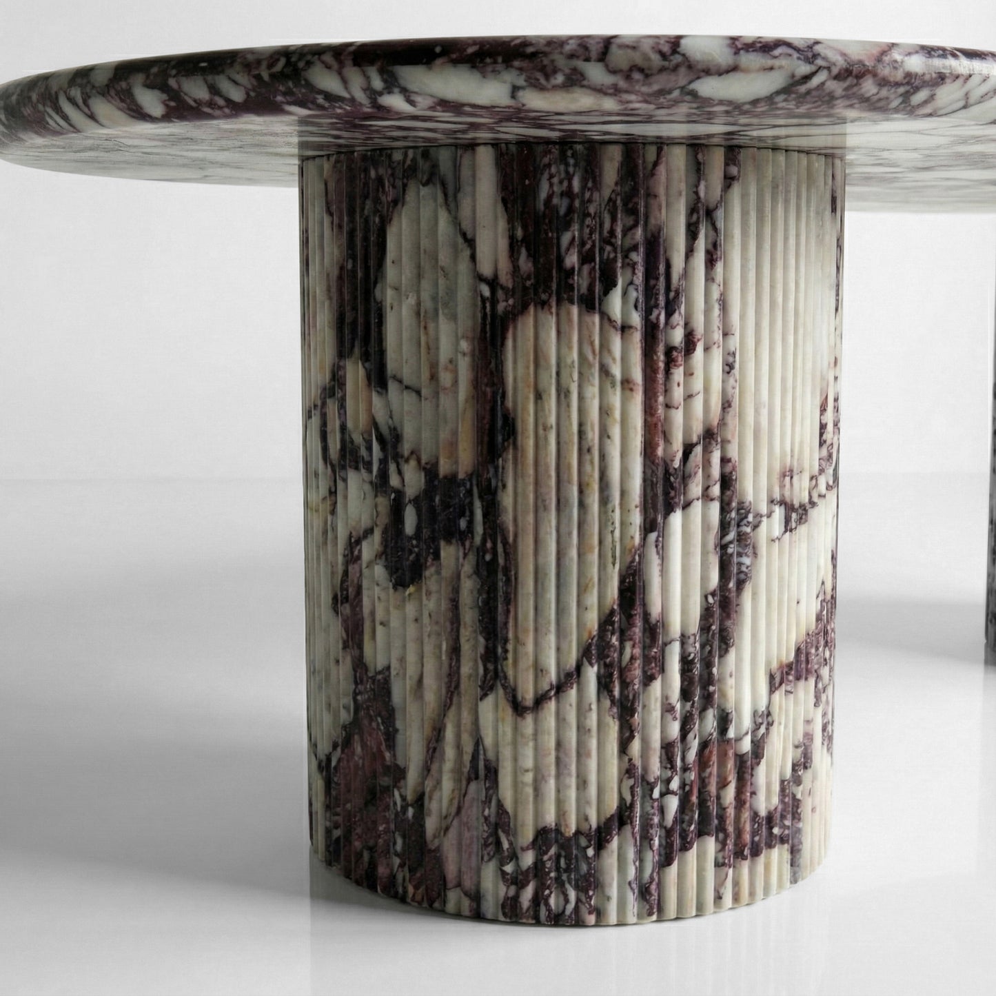 Close-up detail of a fluted marble table base made from Calacatta Viola stone, showcasing the ribbed texture and intricate burgundy and white natural patterns.
