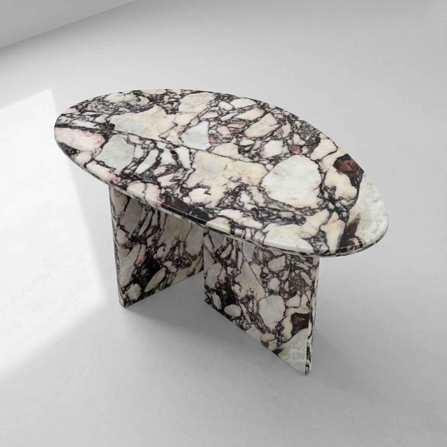 High-angle view of a pebble-shaped coffee table crafted from Calacatta Viola marble, showcasing its unique organic silhouette and bold natural patterns.