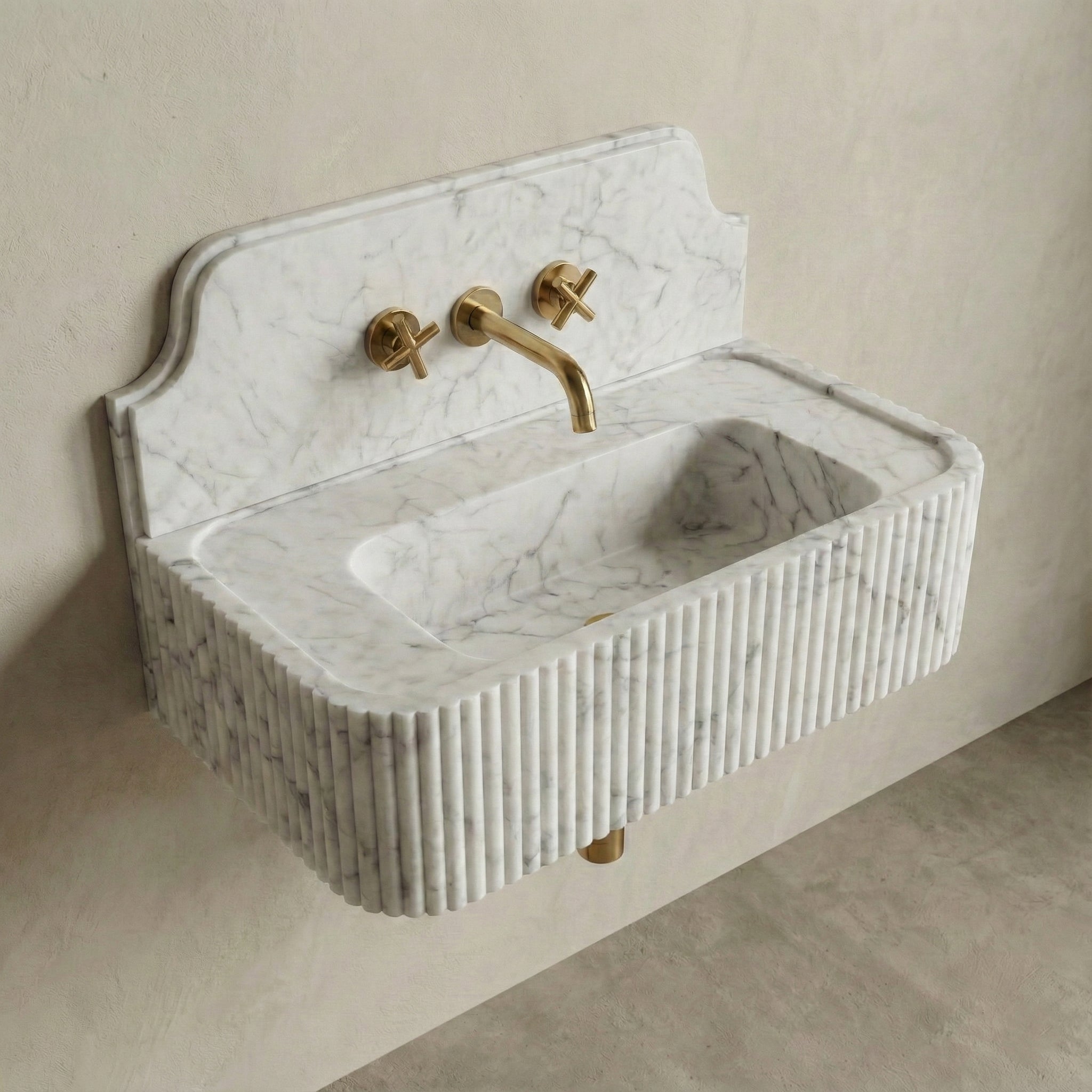 High-angle side view of a vintage-style Carrara marble sink, showcasing the curved stone backsplash, fluted apron, and brass cross-handle faucet.
