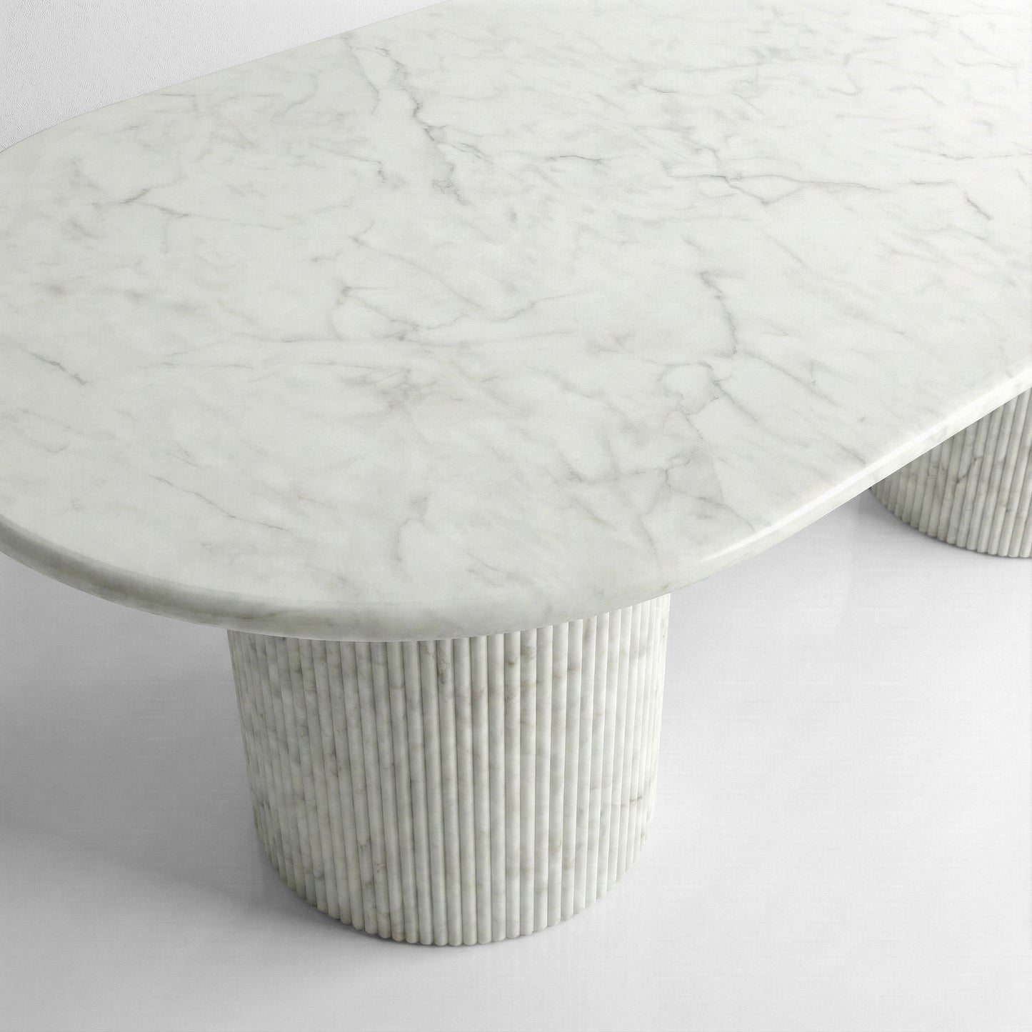 Close-up side profile of a Carrara marble dining table showing the smooth honed white stone surface and subtle grey natural veining.