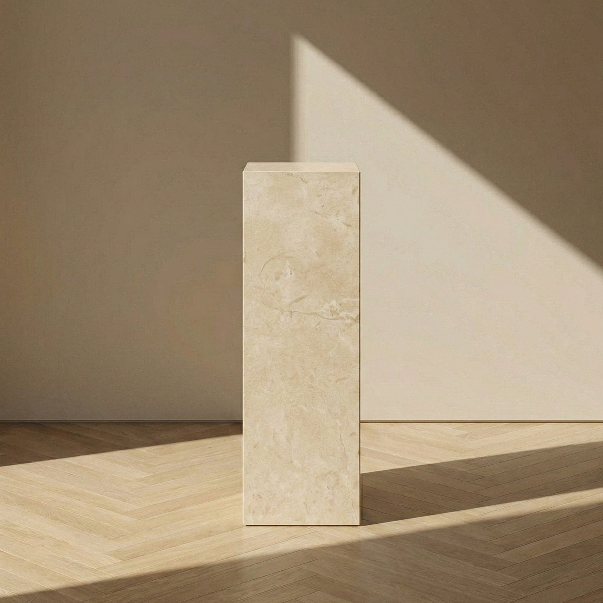 A front-on view of a Crema Marfil marble pedestal stand against a neutral beige wall, emphasizing its elegant vertical proportions and understated natural beauty.