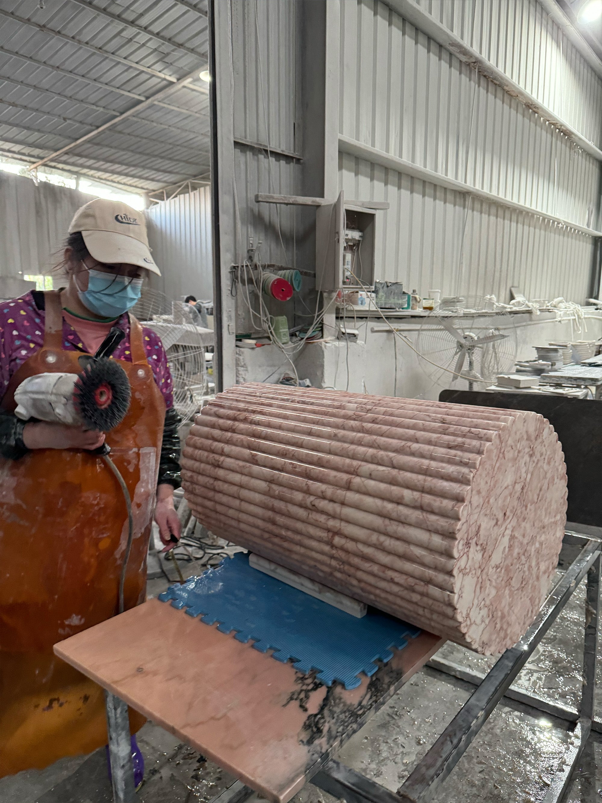 A skilled artisan at the GustavDesign factory hand-polishing a fluted marble column, demonstrating the detailed stone fabrication required for luxury interior commissions.