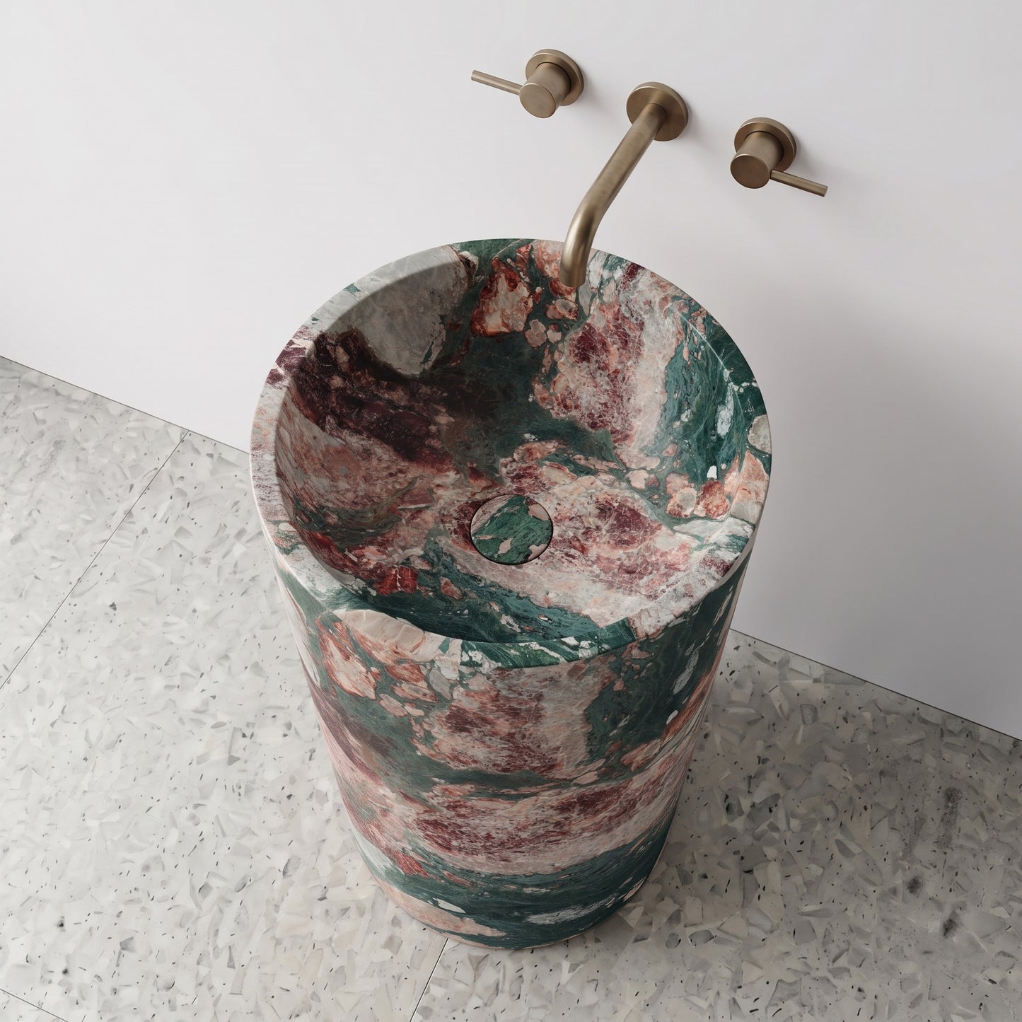 High-angle top view of a Four Seasons marble cylindrical pedestal sink highlighting vivid emerald, blush, and burgundy veining with matching stone drain cap.