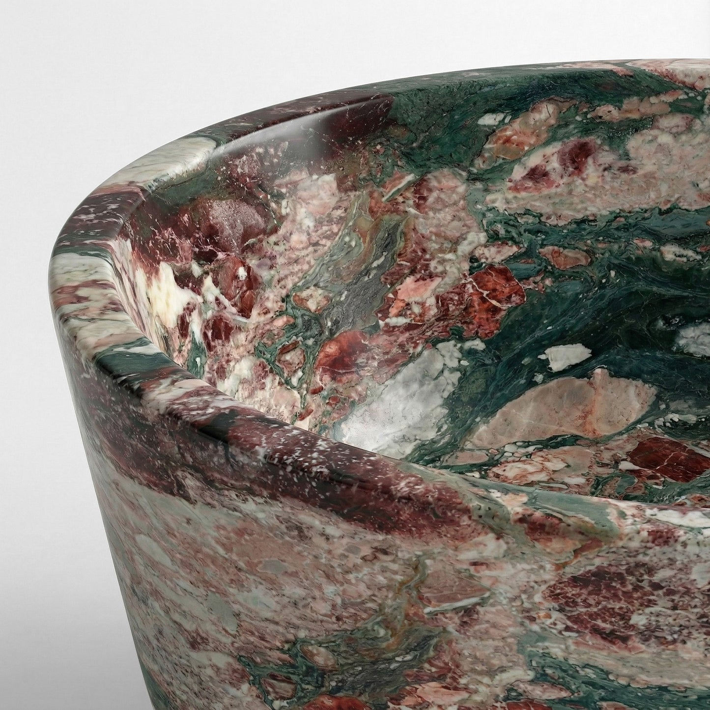 Close-up detail of a Four Seasons marble bathtub rim highlighting the complex brecciated texture with patches of violet, emerald, and gold minerals.