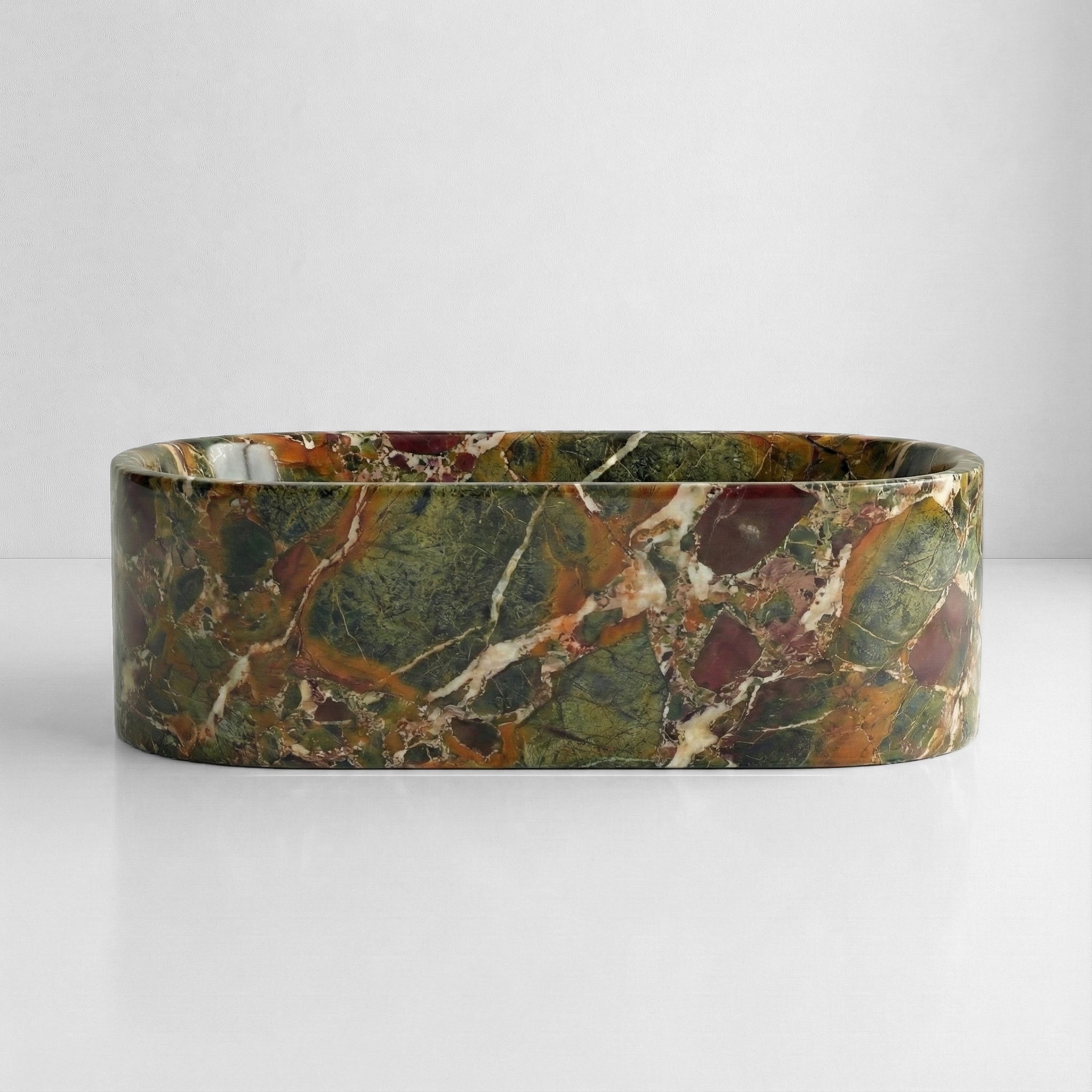 Front elevation of a solid stone oval bathtub carved from exotic Four Seasons marble, featuring dramatic brecciated patterns in earth tones.