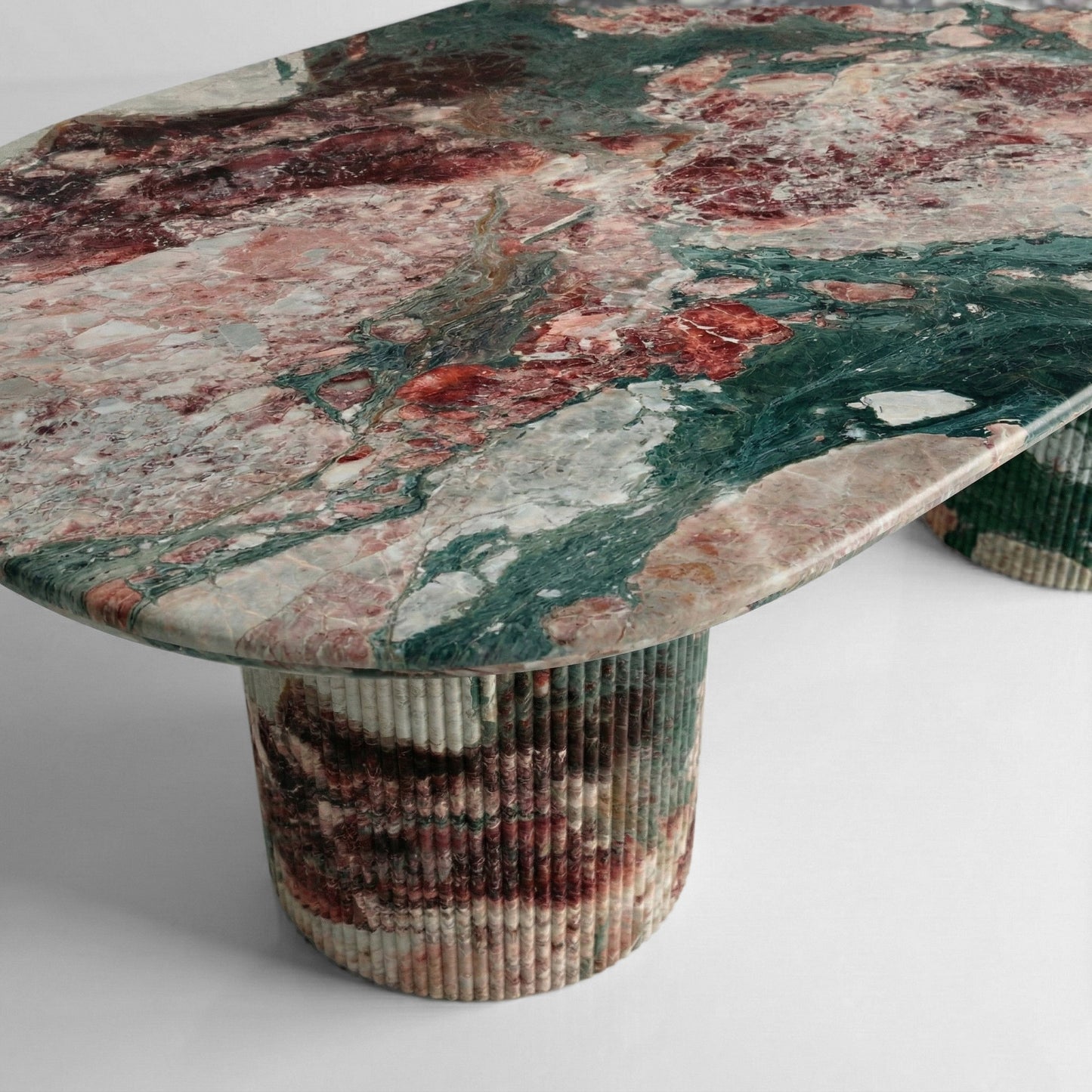 Side profile of a luxury Four Seasons stone dining table showing the thick polished edge and matching ribbed pedestal legs in rich earth tones.