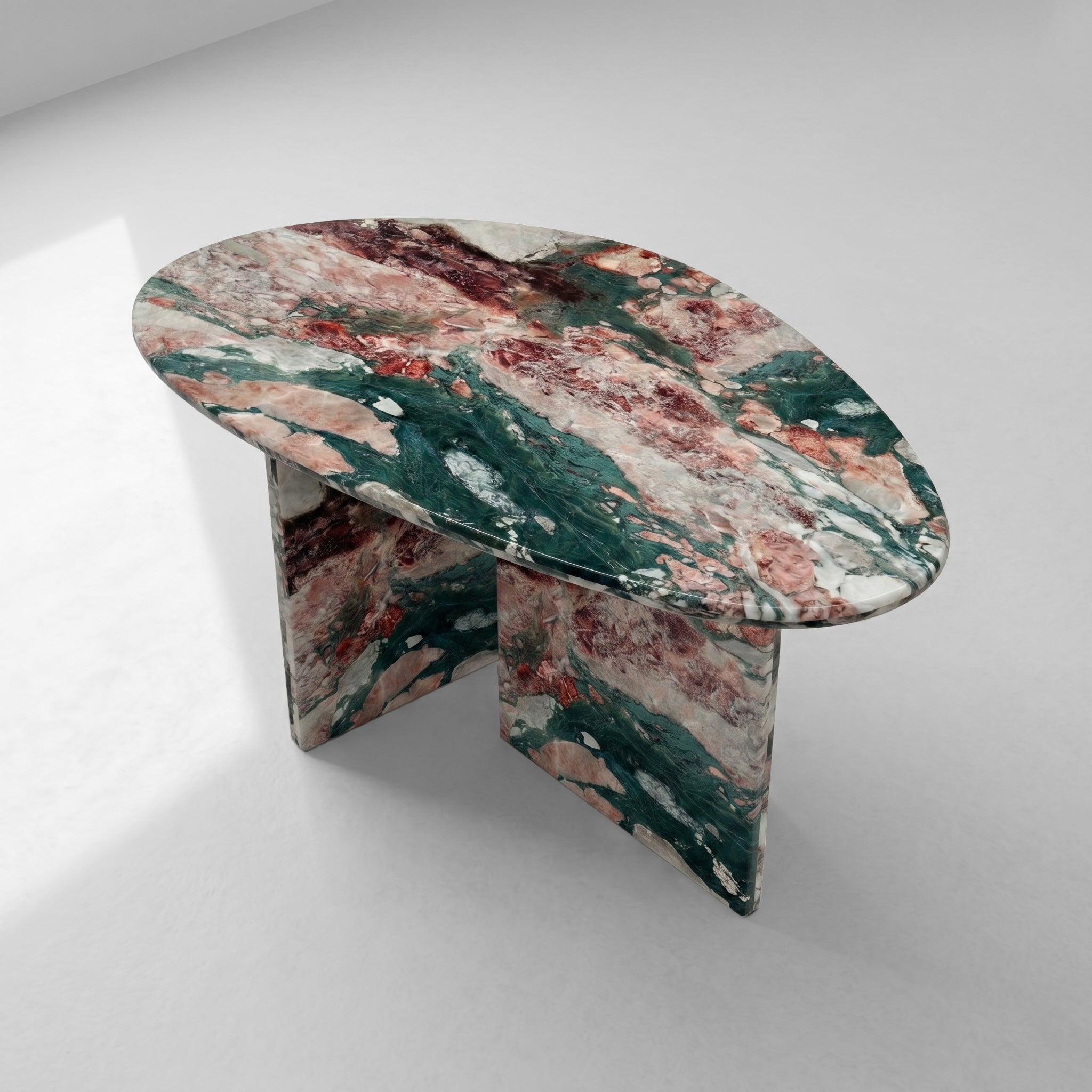 High-angle view of an organic pebble-shaped coffee table crafted from Four Seasons marble, highlighting its unique silhouette and diverse natural color palette.